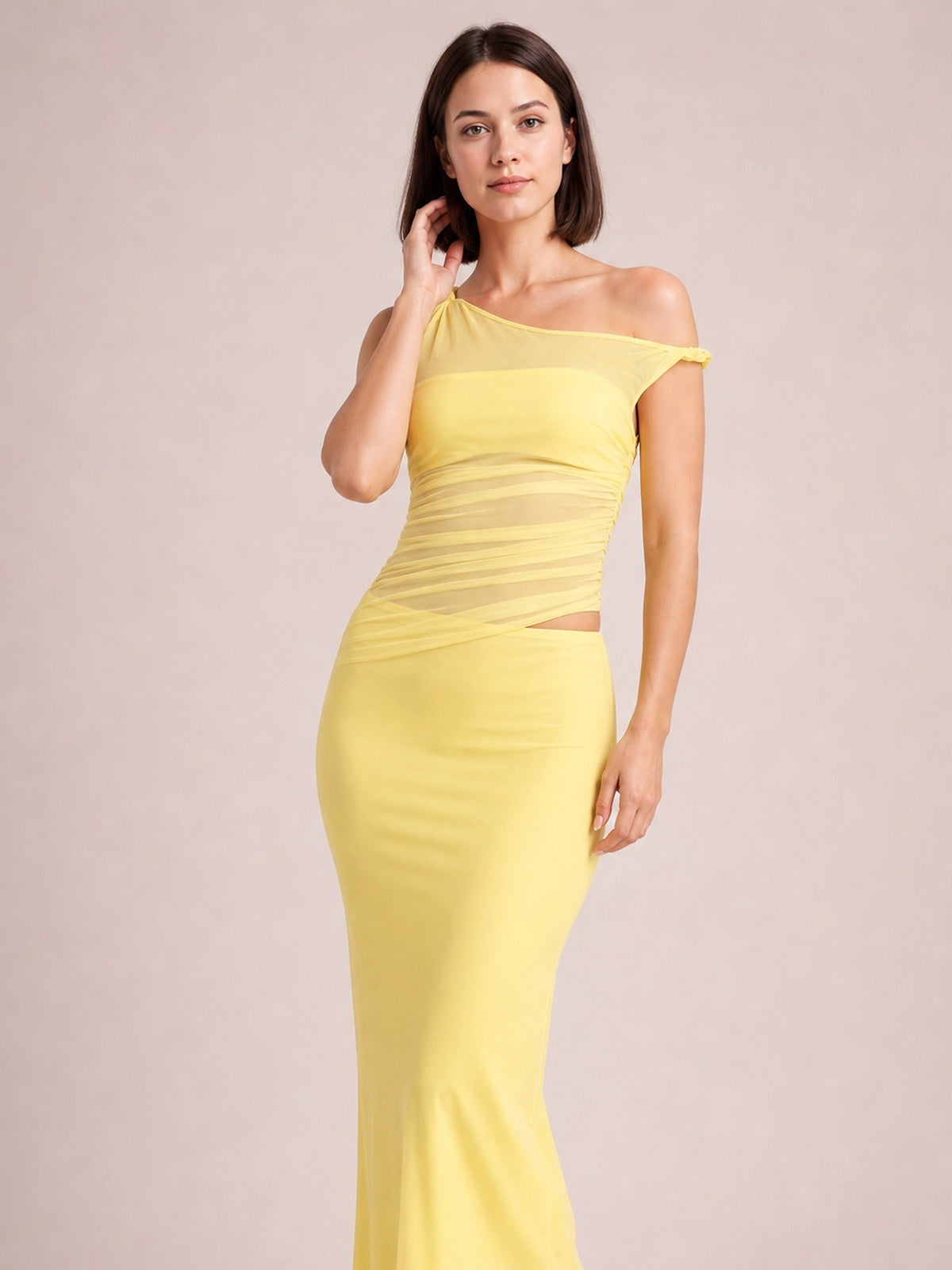 A model poses in a yellow asymmetrical cutout sleeveless maxi dress with twisted ruching, a figure-skimming silhouette, and a sleek ankle-length skirt.