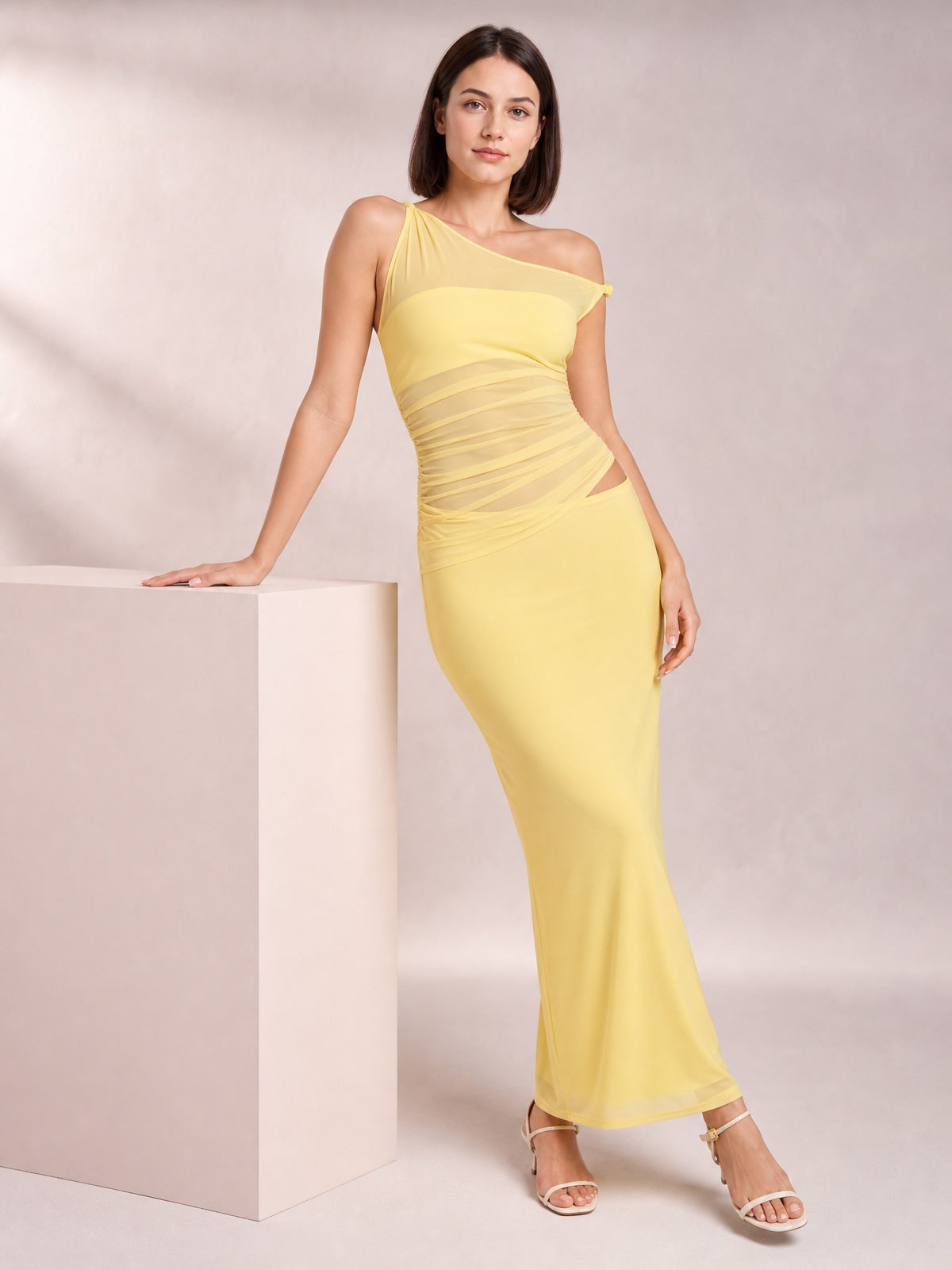 Model poses in a yellow asymmetrical cutout sleeveless maxi dress with a twisted, ruched bodice and figure-skimming ankle-length silhouette.