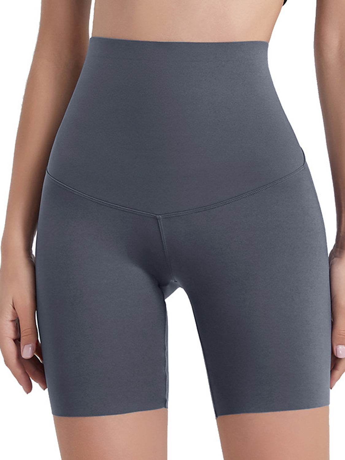 Model wears dark gray wide-waistband sports shorts with a high-rise silhouette, smooth stretch fabric, curved seam construction, and fitted mid-thigh length.