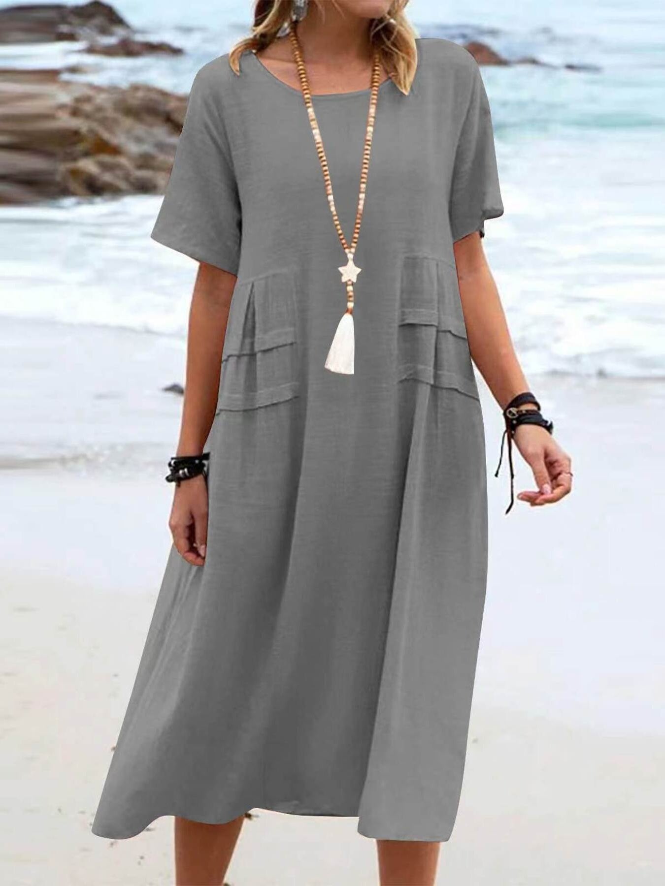 Plus size loose midi dress with short sleeves and pockets shown in cream and black by the beach
