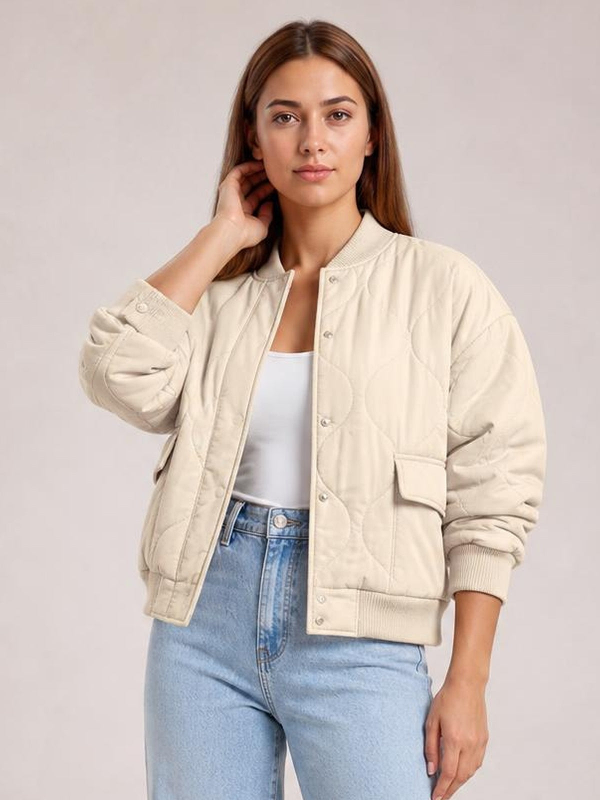 Model poses in a cream baseball-collar snap-down jacket with long sleeves, ribbed cuffs and hem, quilted construction, and front flap pockets.