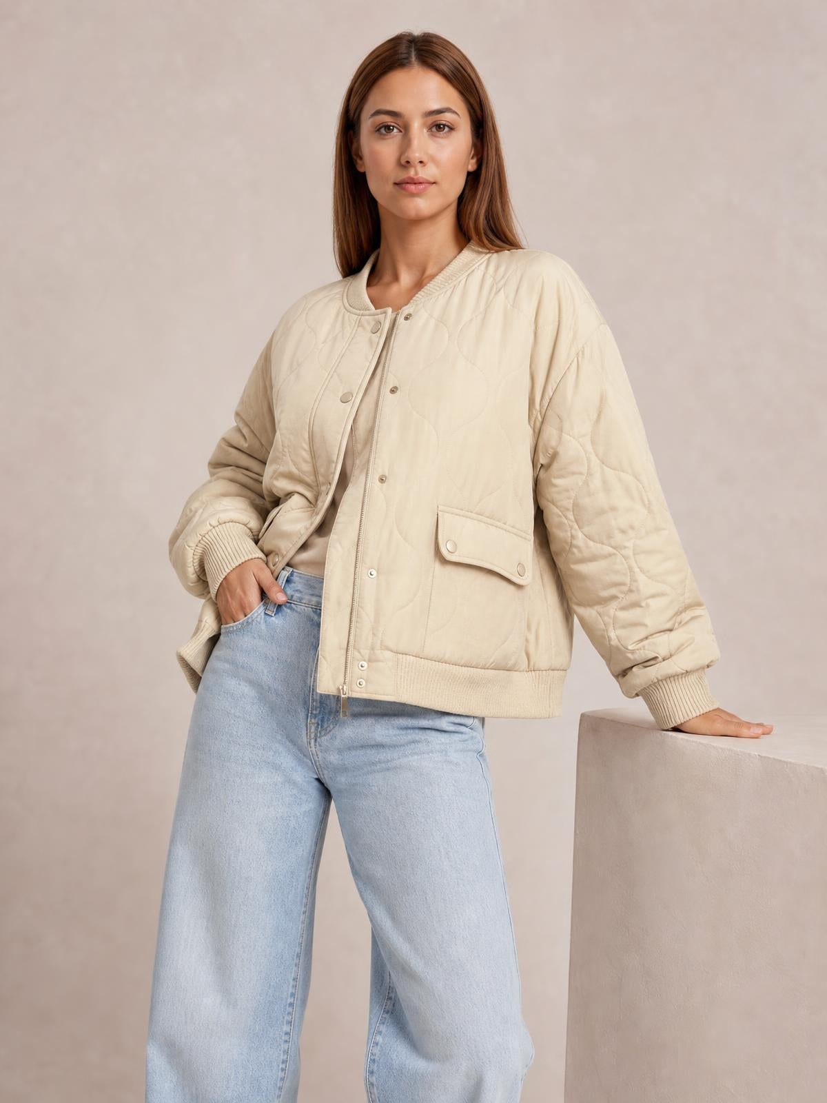 Model wears a cream quilted baseball-collar jacket with a snap-down front, long sleeves, ribbed cuffs and hem, flap pockets, and a relaxed silhouette.