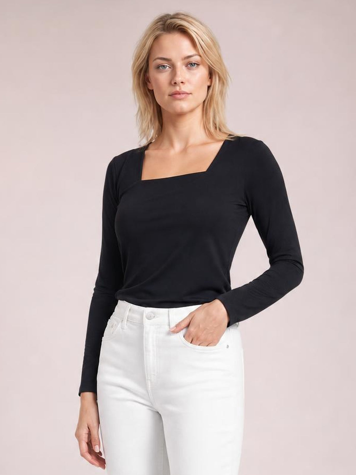 Model poses with one hand in her pocket wearing a fitted black asymmetrical-neck long-sleeve top with a clean, opaque silhouette.