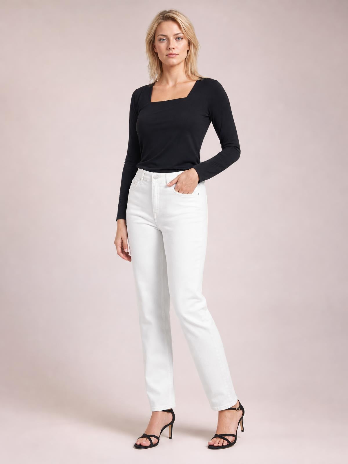 Model stands with one hand in her pocket wearing a black asymmetrical neck long sleeve top with a fitted silhouette and clean construction.