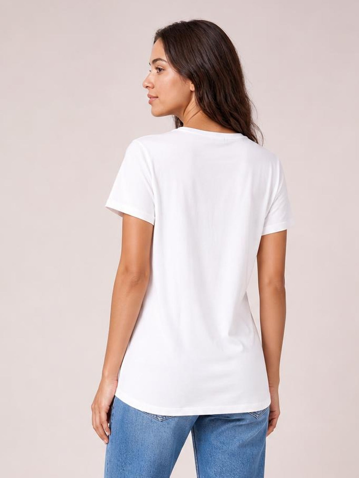 A model looks over her shoulder wearing a white bamboo T-shirt with short sleeves, a relaxed silhouette, and a curved high-low hem.