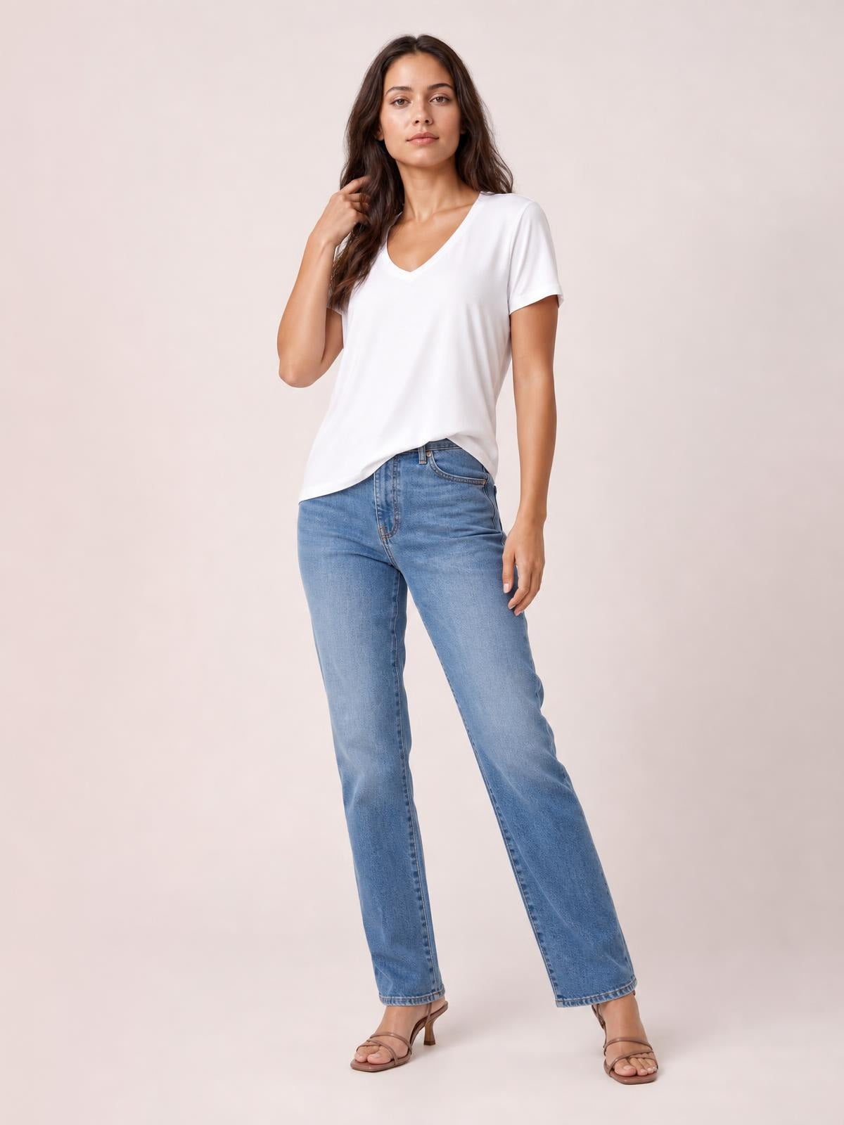 Model poses in a white bamboo V-neck T-shirt with short sleeves and a relaxed high-low hem, styled with blue jeans.