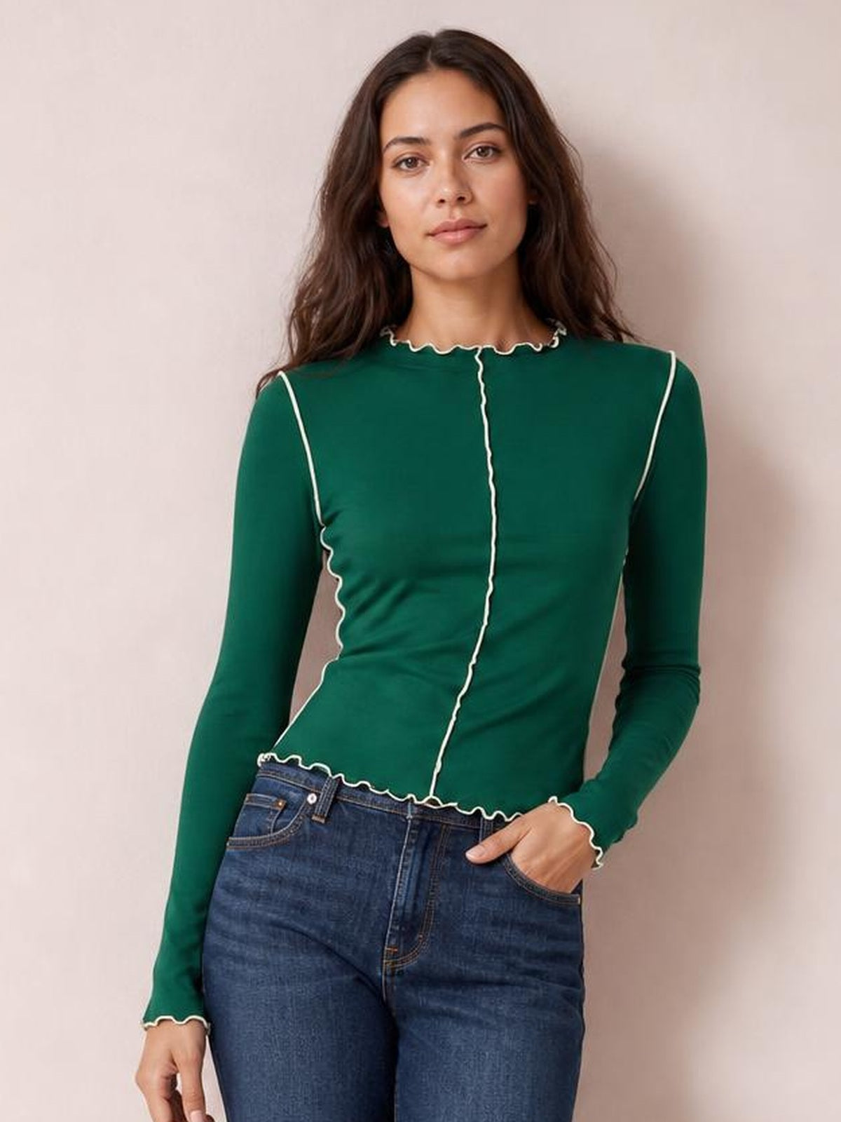 Model wears a fitted forest-green mock neck long sleeve T-shirt with white contrast trim, scalloped edges, and a defined seamed silhouette.