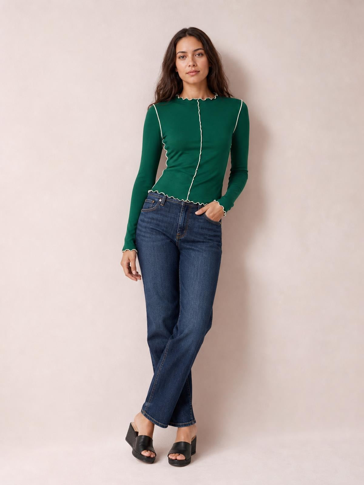 Model poses in a green contrast-trim mock neck long sleeve T-shirt with a fitted silhouette, scalloped edging, and center seam detail.