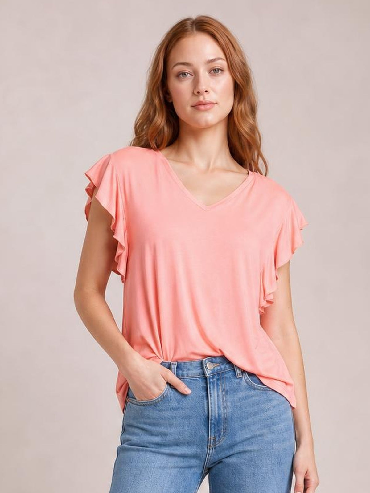 Model poses in a coral bamboo short-sleeve T-shirt with a notched V-neck, ruffled sleeves, and a relaxed silhouette.