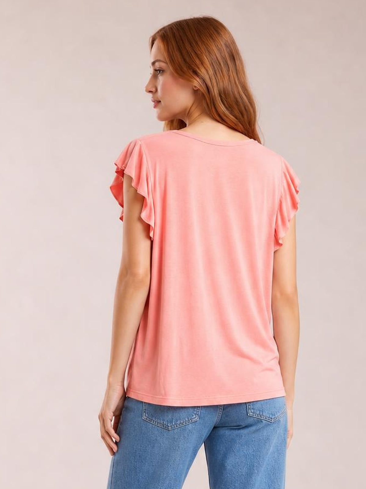 Model shown from the back wearing a coral bamboo T-shirt with a relaxed silhouette, notched neckline, ruffled short sleeves, and straight hem.