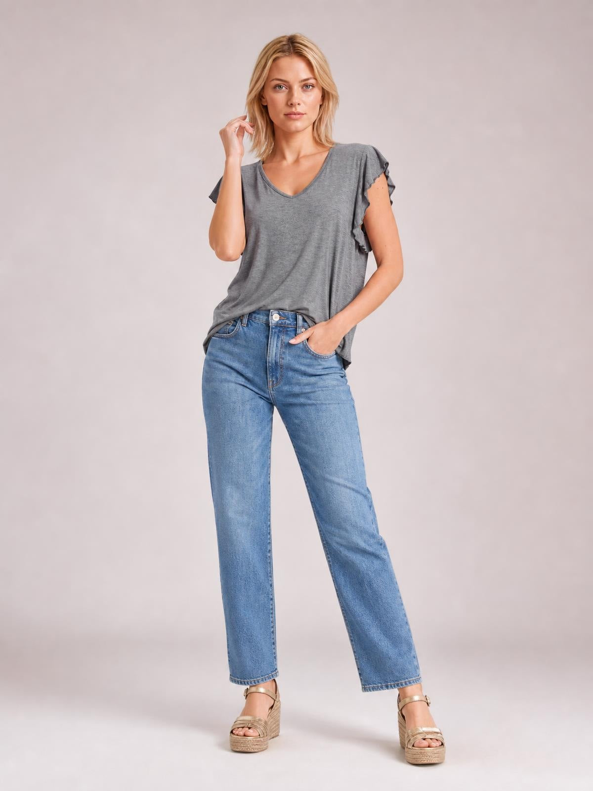 Model poses in a gray bamboo T-shirt with a notched V-neck, ruffled short sleeves, and a relaxed, stretchy silhouette.