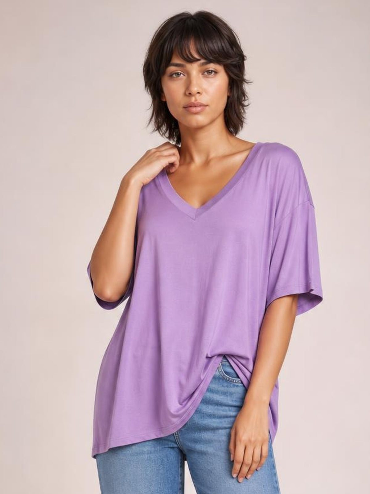 Model poses in a lavender Bamboo V-Neck Drop Shoulder T-Shirt with an oversized silhouette, short sleeves, and a curved hem.