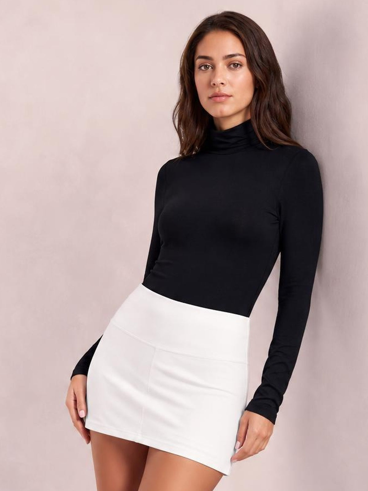 Model wears a fitted black mock neck long sleeve bodysuit with an opaque, smooth silhouette and moderate stretch, standing with a slight lean.