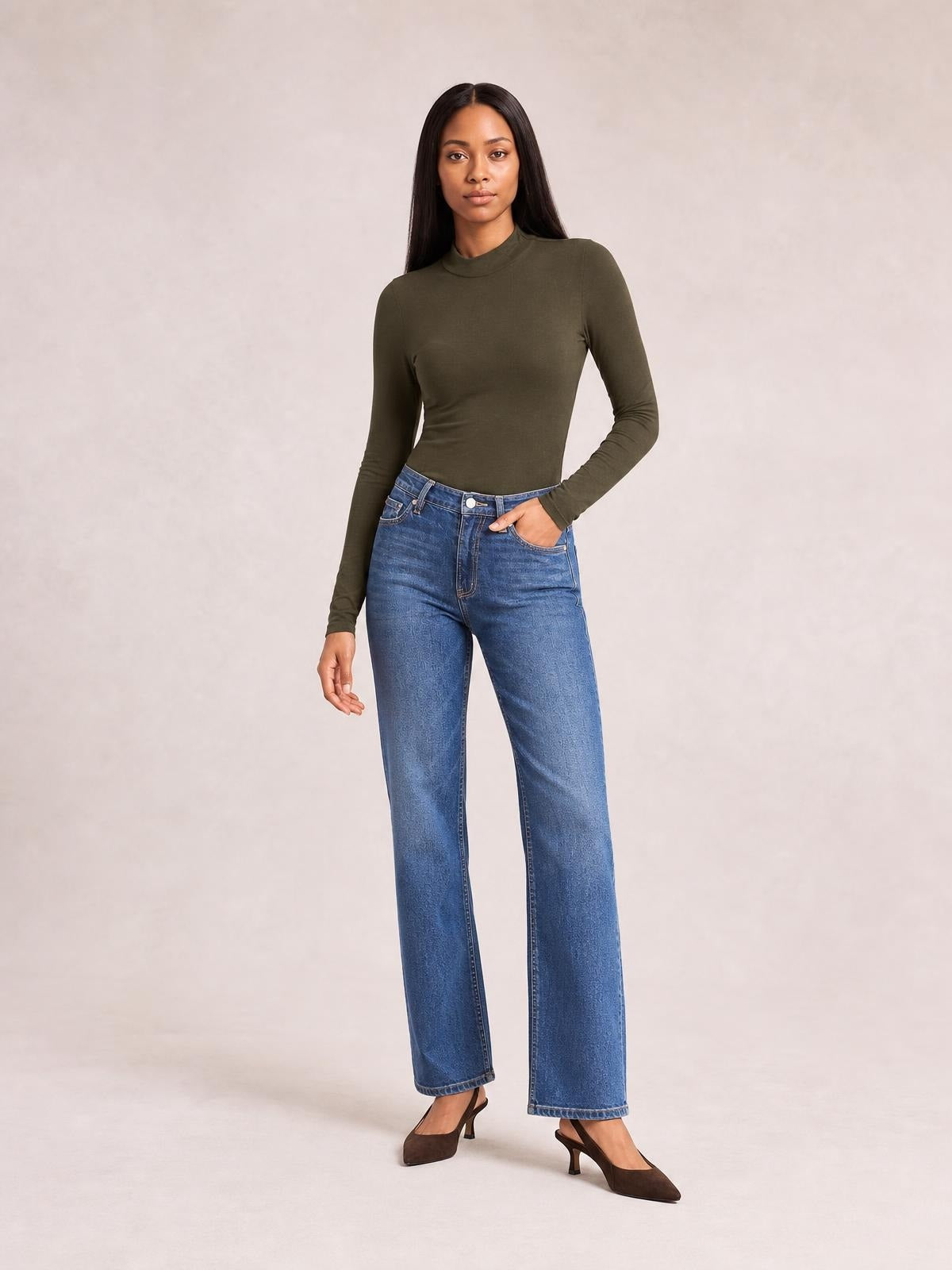 Model wears an olive mock neck long sleeve bodysuit with a smooth, fitted silhouette, standing with one hand in her jeans pocket.