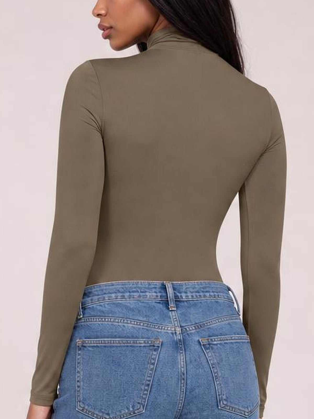 A model poses with her back turned in an olive mock neck long sleeve bodysuit with a smooth, close-fitting silhouette and stretch construction.