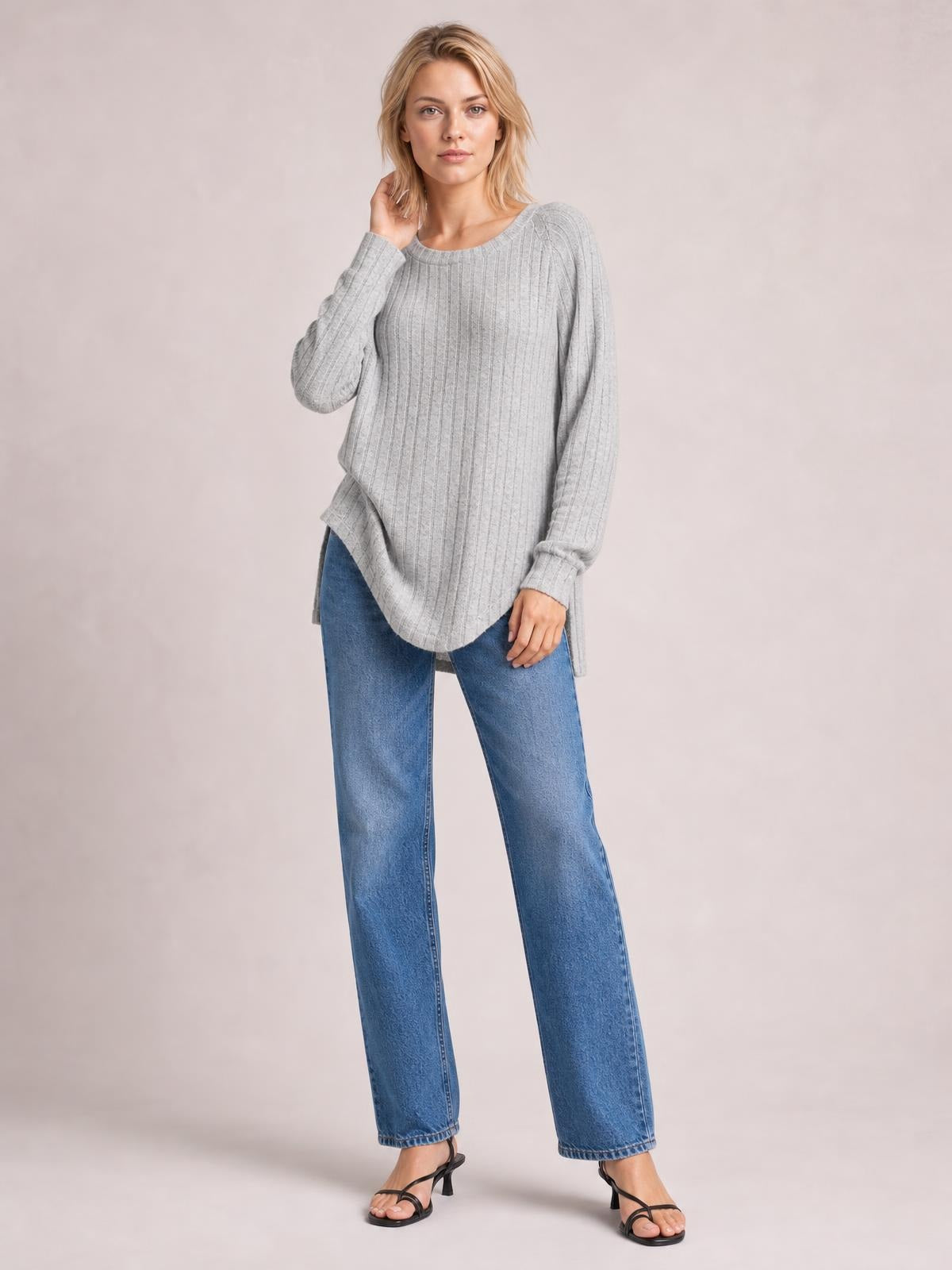 A model poses in a gray ribbed round neck slit T-shirt with long sleeves, a relaxed silhouette, curved hem, and visible side slits.