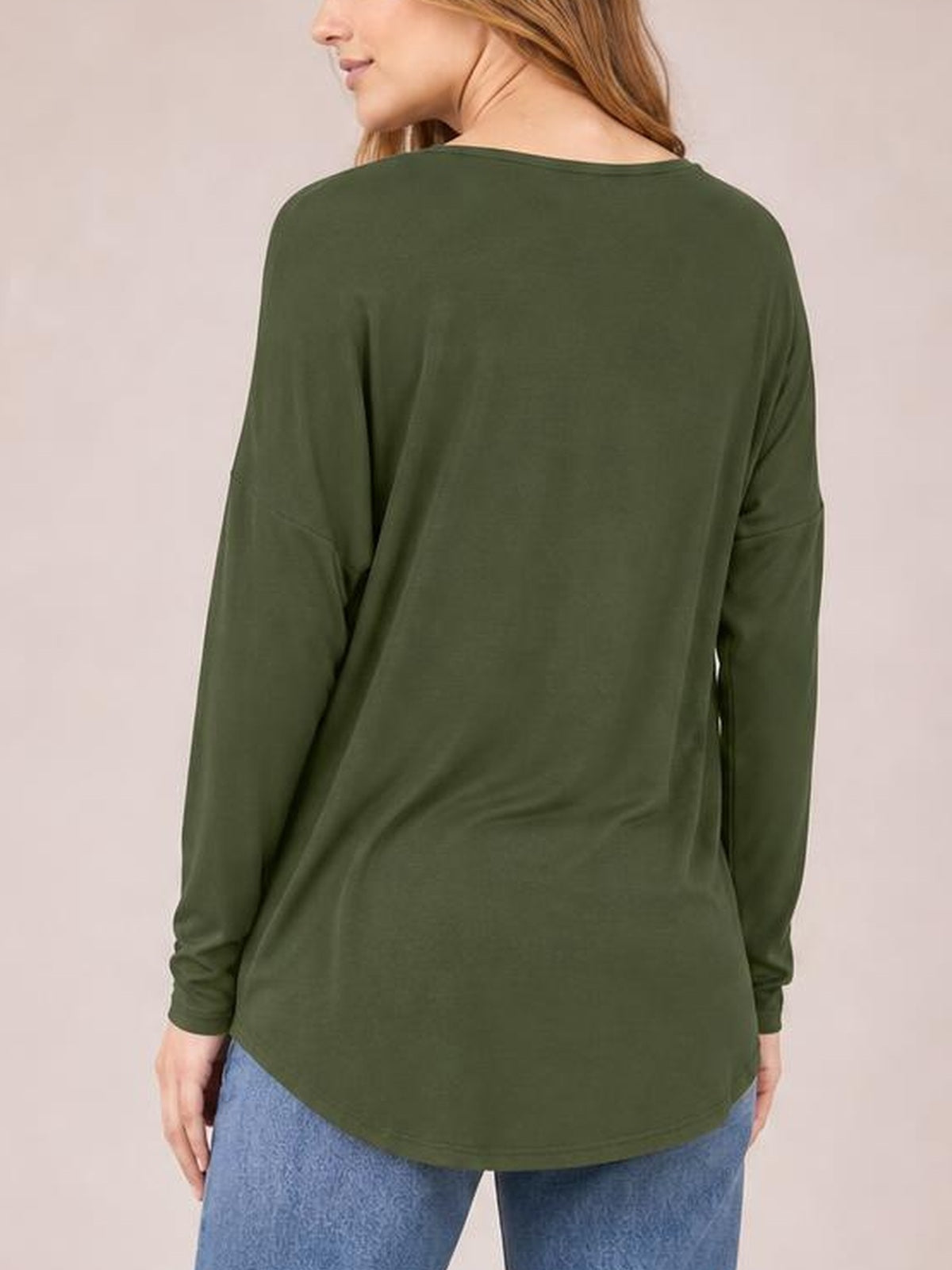 A model is shown from behind wearing an olive green round neck dropped shoulder T-shirt with long sleeves, a relaxed silhouette, and curved hem.