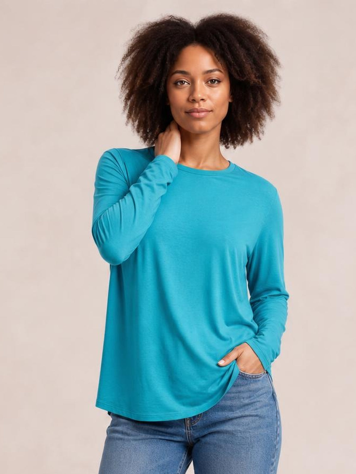 Model poses in a bright teal round neck dropped shoulder T-shirt with long sleeves, a relaxed loose silhouette, and a slightly curved hem.