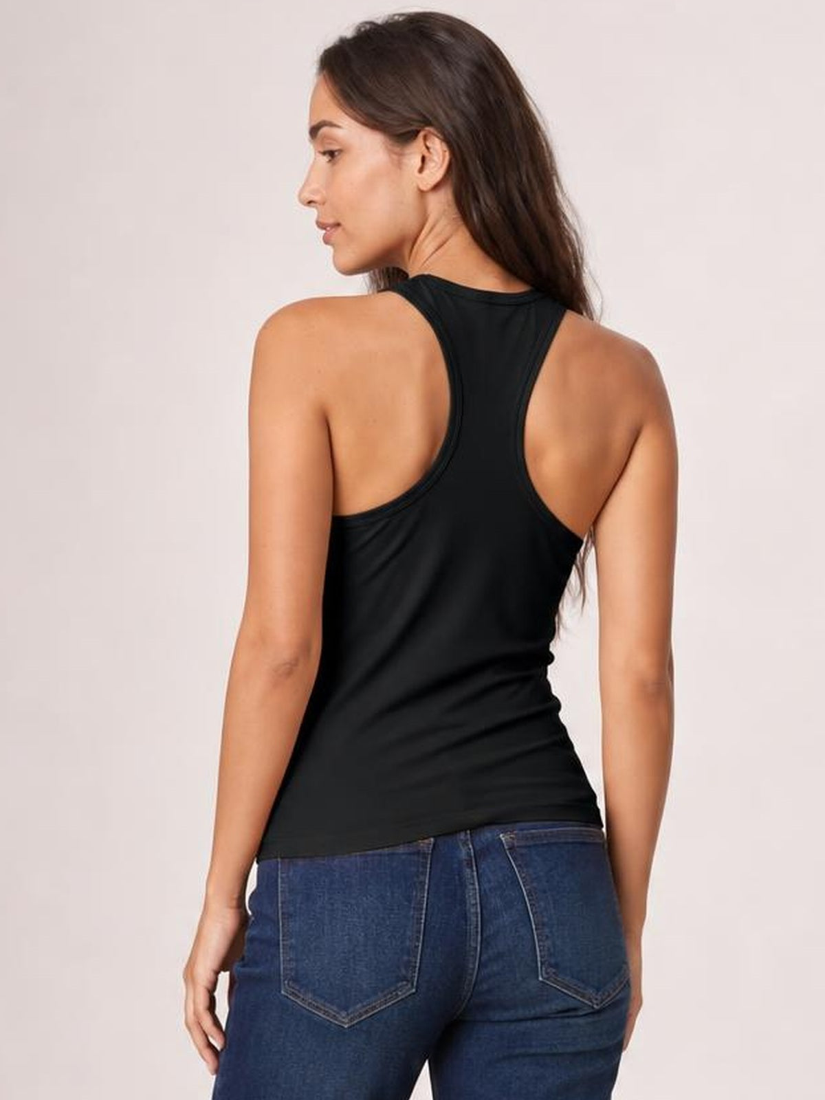 Model turned away shows a black racerback tank with a round neckline, wide shoulder straps, fitted silhouette, and smooth, slightly stretchy construction.