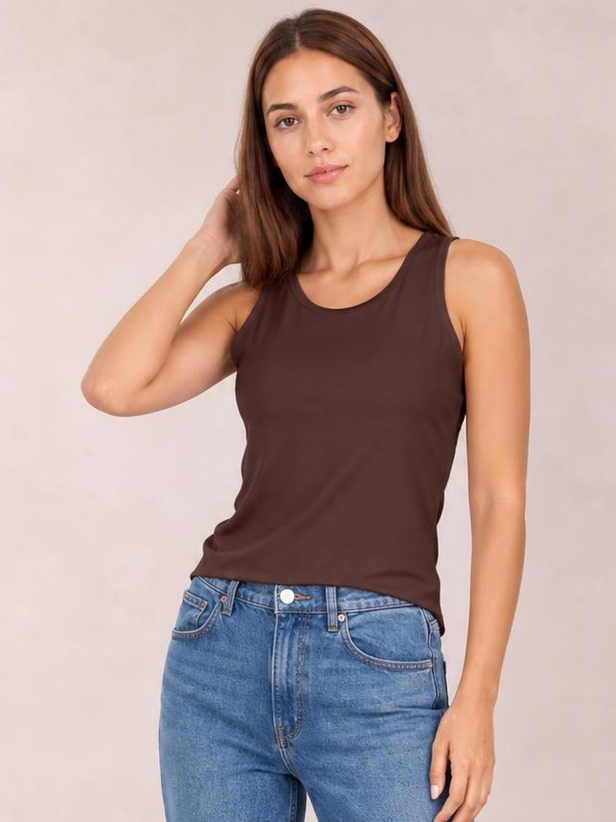 Model poses in a brown round neck racerback tank with a slim silhouette, wide shoulder straps, and smooth opaque construction.
