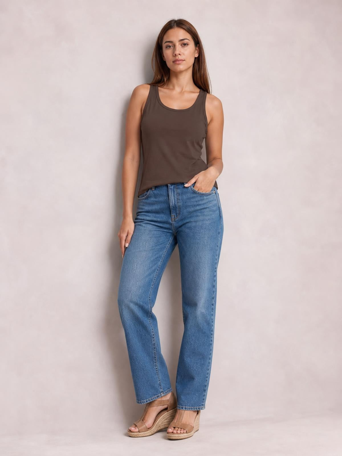 A model stands in a relaxed pose wearing a dark brown round neck tank with wide shoulder straps and a smooth, fitted silhouette.