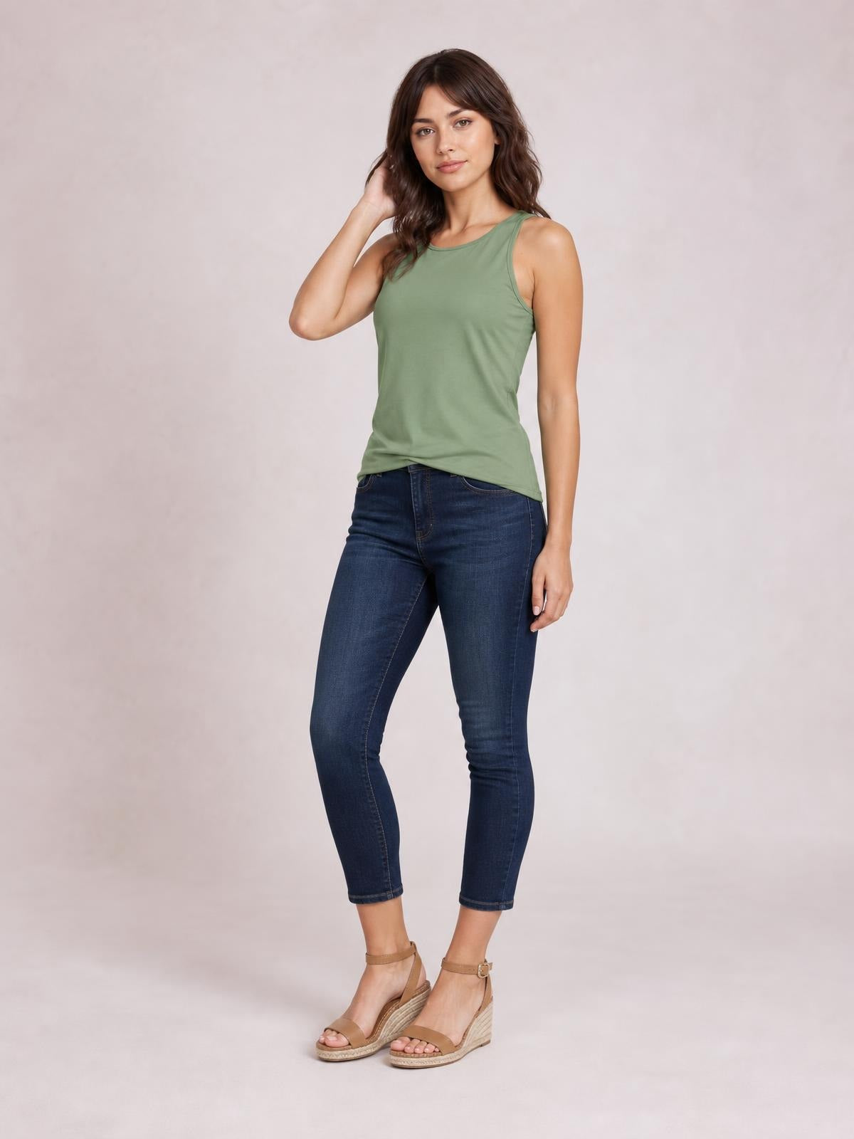 A model poses in a sage green round neck racerback tank with a basic sleeveless cut, slim silhouette, and subtle stretch.
