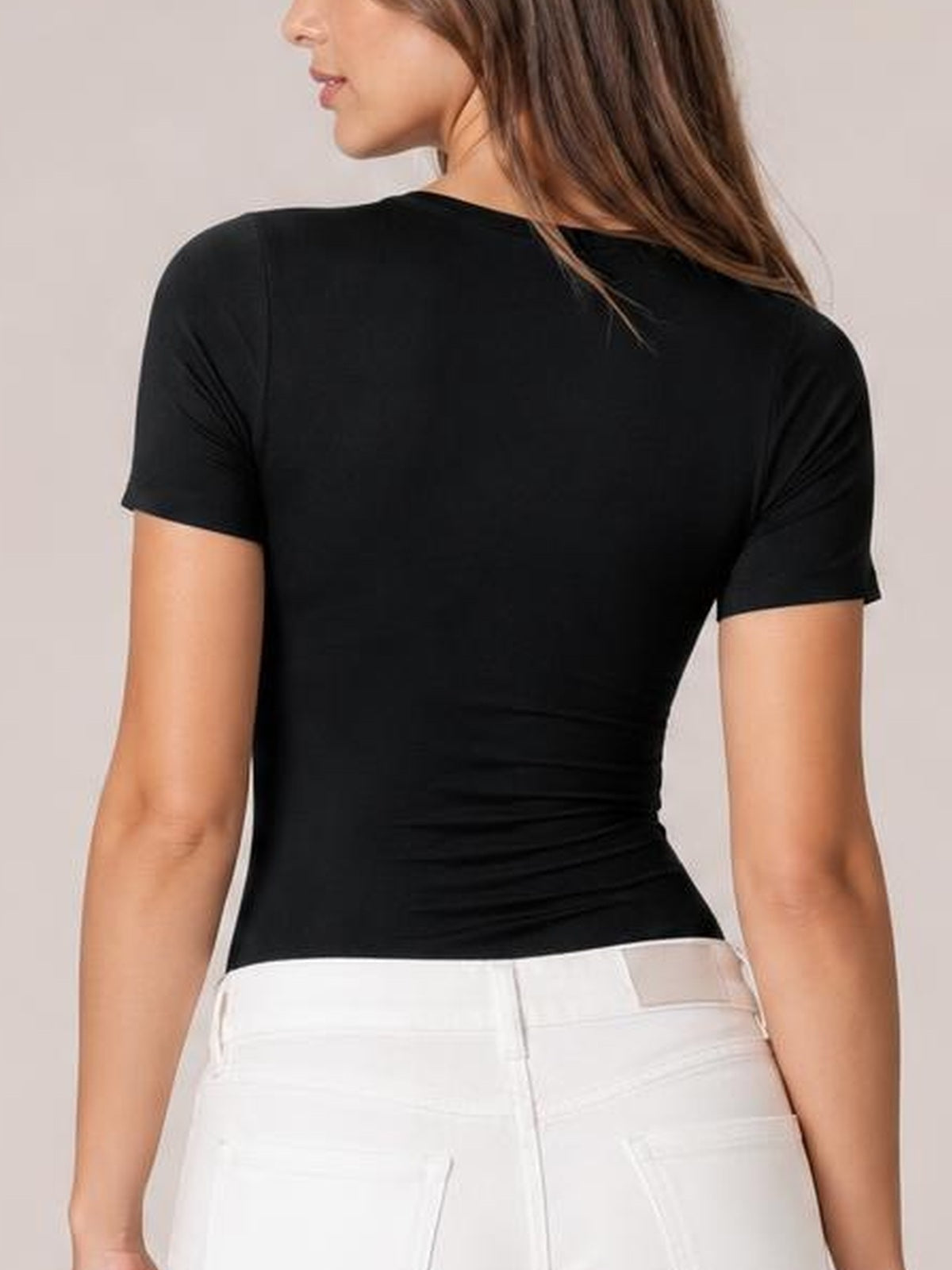 Model shown from behind wearing a black round neck short sleeve bodysuit with a smooth, fitted silhouette and moderate stretch.