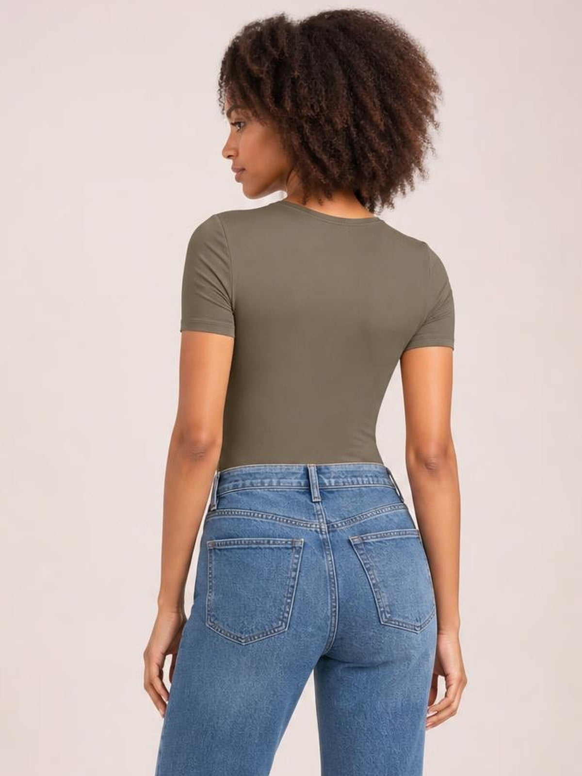 Model shown from the back in an olive round neck short sleeve bodysuit with a smooth, fitted silhouette and clean construction.