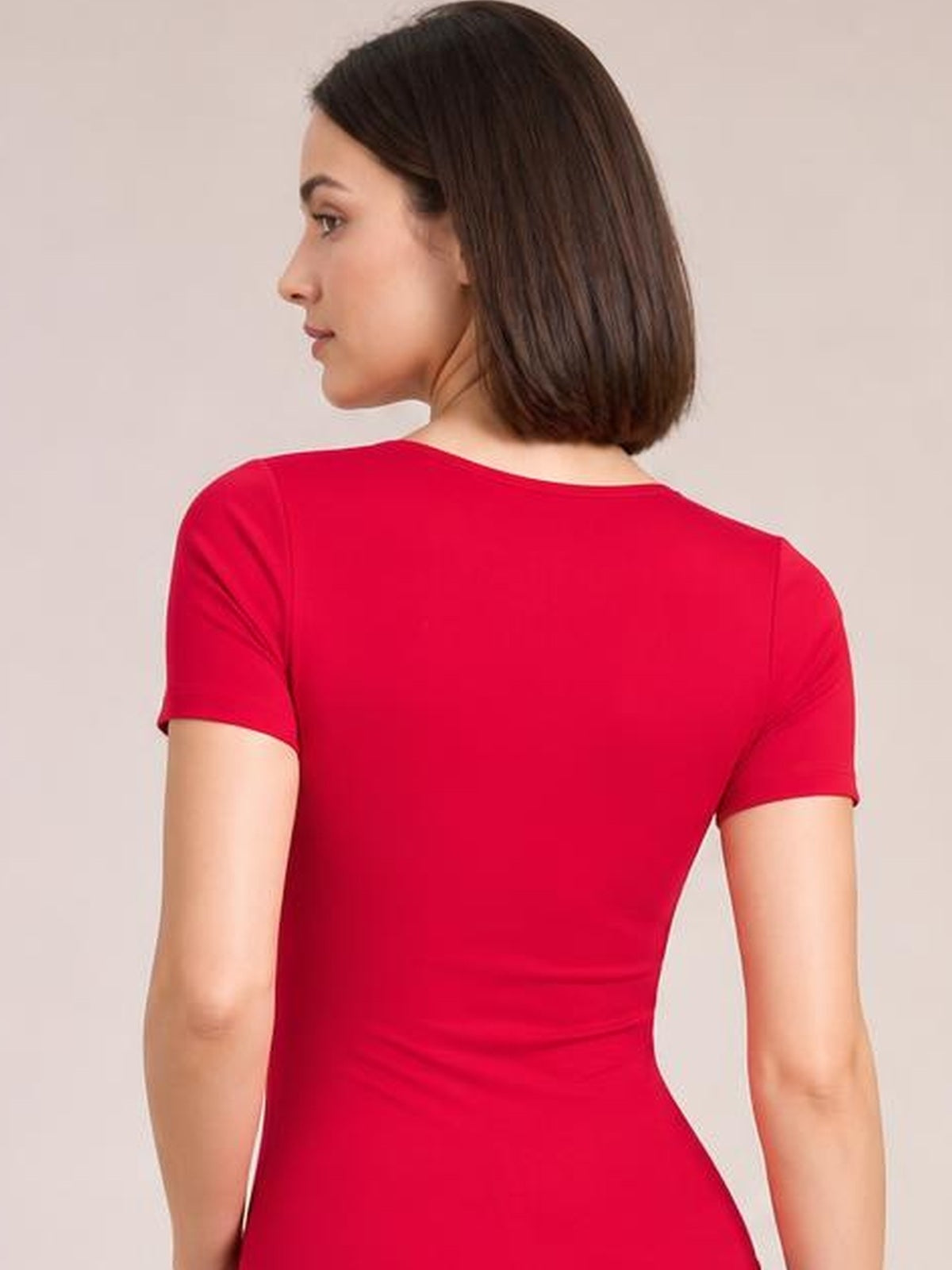 Model shown from the back in a red round neck short sleeve bodysuit with a smooth, fitted silhouette and moderate stretch.