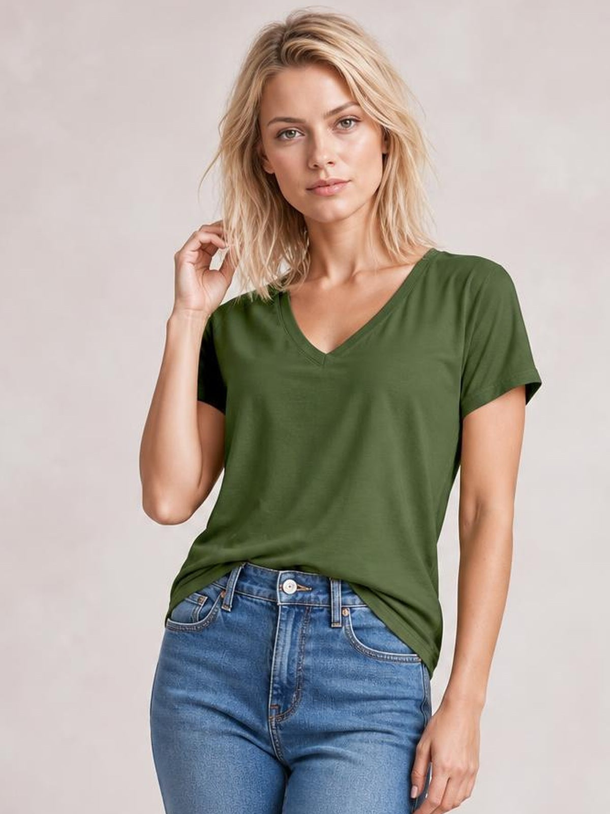 Model poses in a forest green V-neck T-shirt with short sleeves, a relaxed silhouette, and a longer high-low hem with side slit.
