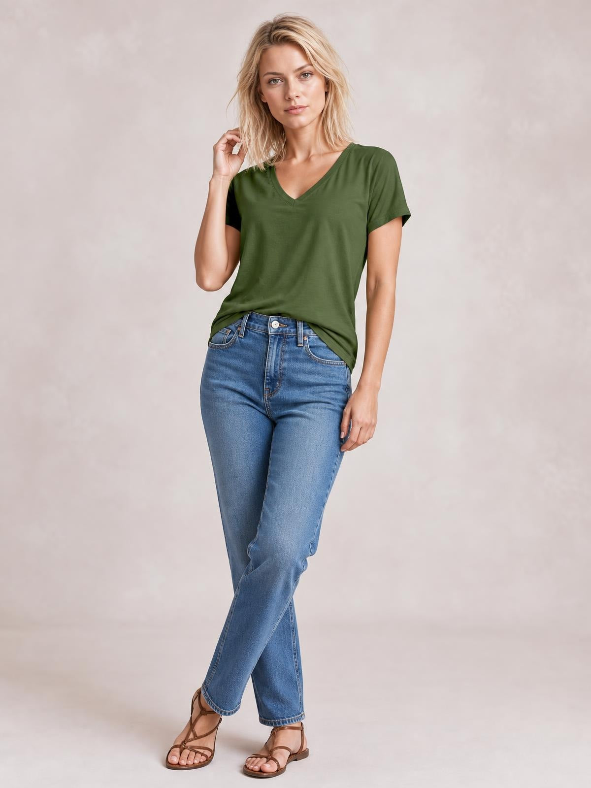 Model wears an olive green V-neck high-low T-shirt with short sleeves and a relaxed silhouette, posed with one hand touching her hair.