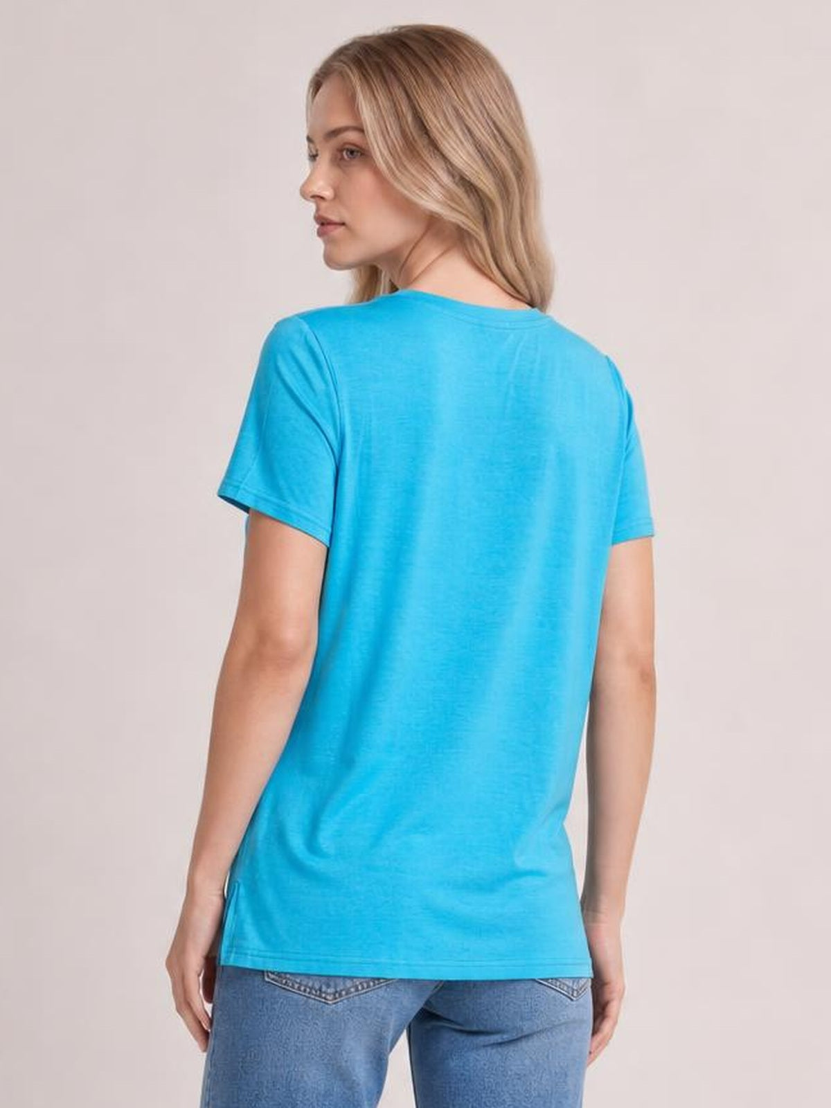Model shown from the back in a bright blue V-neck high-low T-shirt with short sleeves, relaxed fit, and side slit construction.