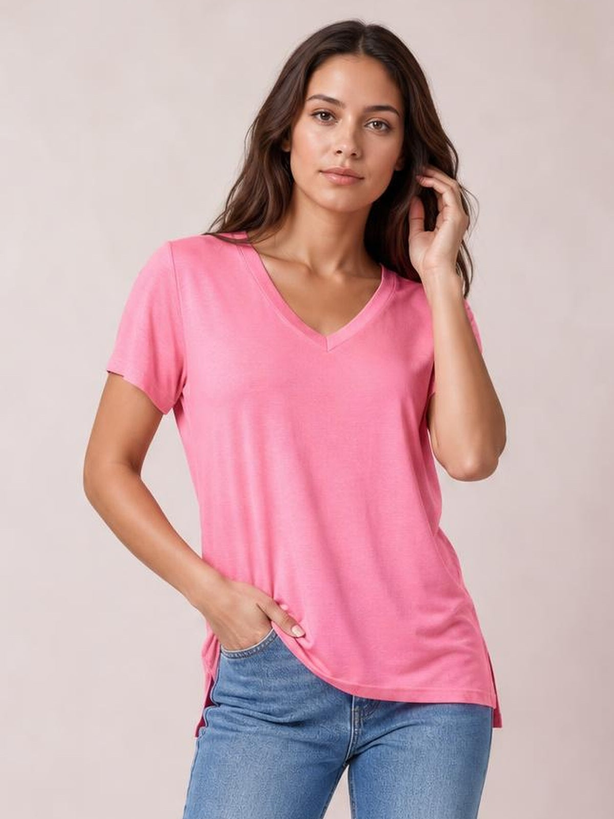 A model poses in a pink V-neck high-low T-shirt with short sleeves, a relaxed silhouette, and a longer back hem with side slit.