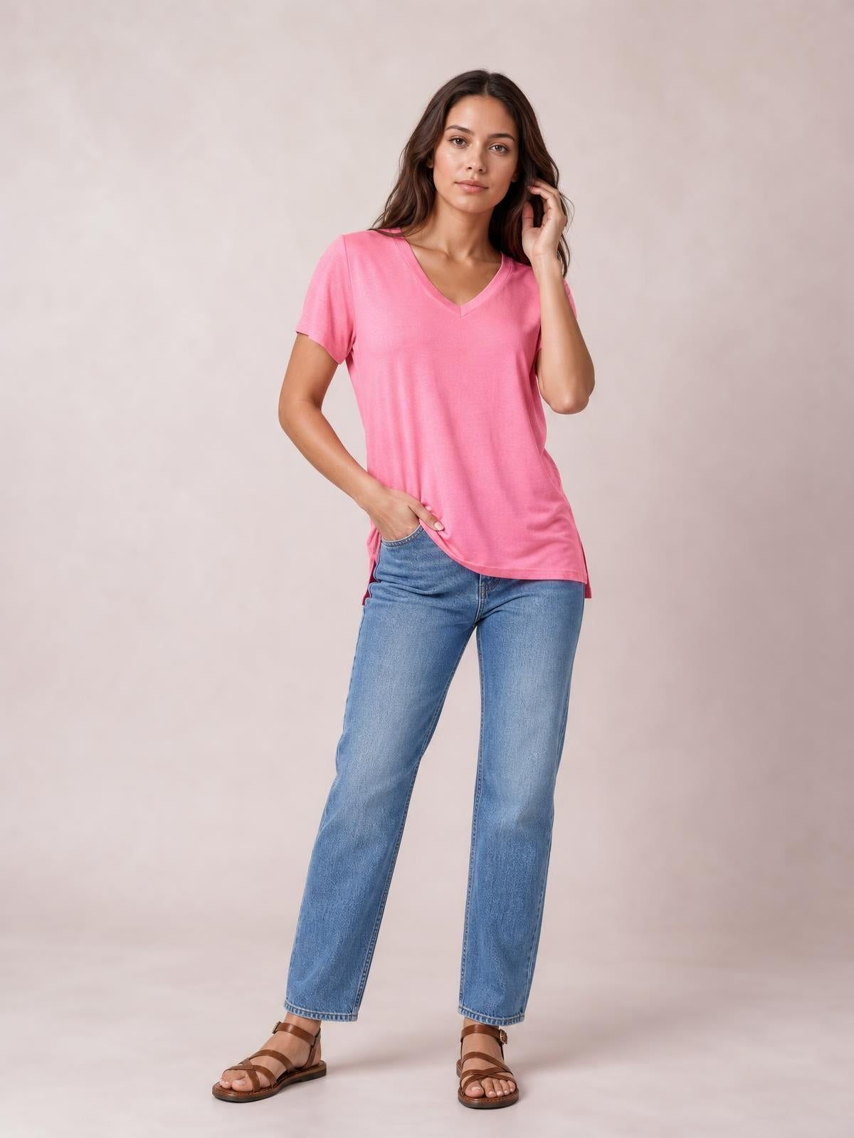 Model poses in a pink V-neck high-low T-shirt with a relaxed silhouette, short sleeves, and a visible side slit.