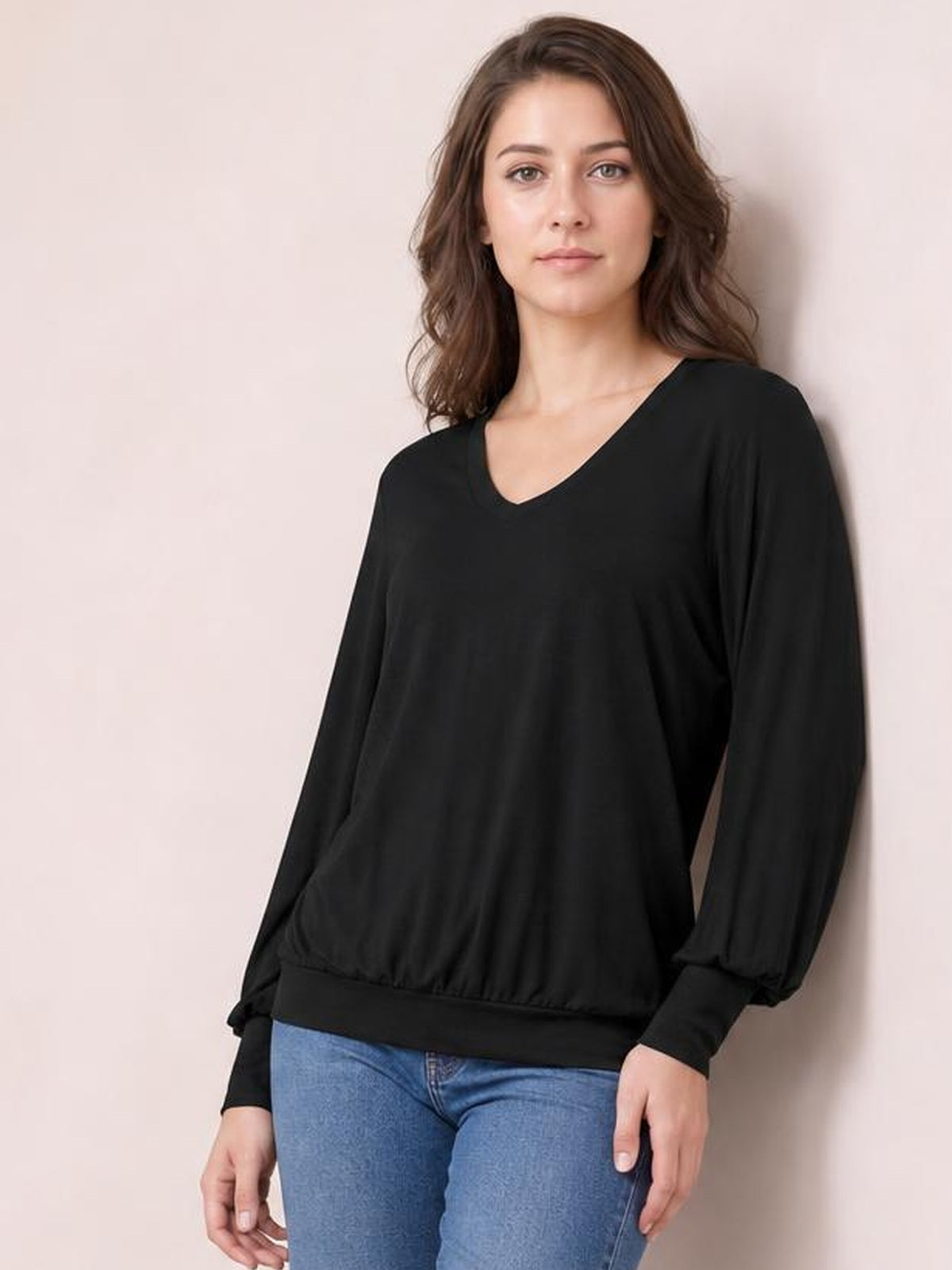 Model wearing a black V-neck top with voluminous lantern sleeves, fitted cuffs, and a gathered hem for a relaxed silhouette.