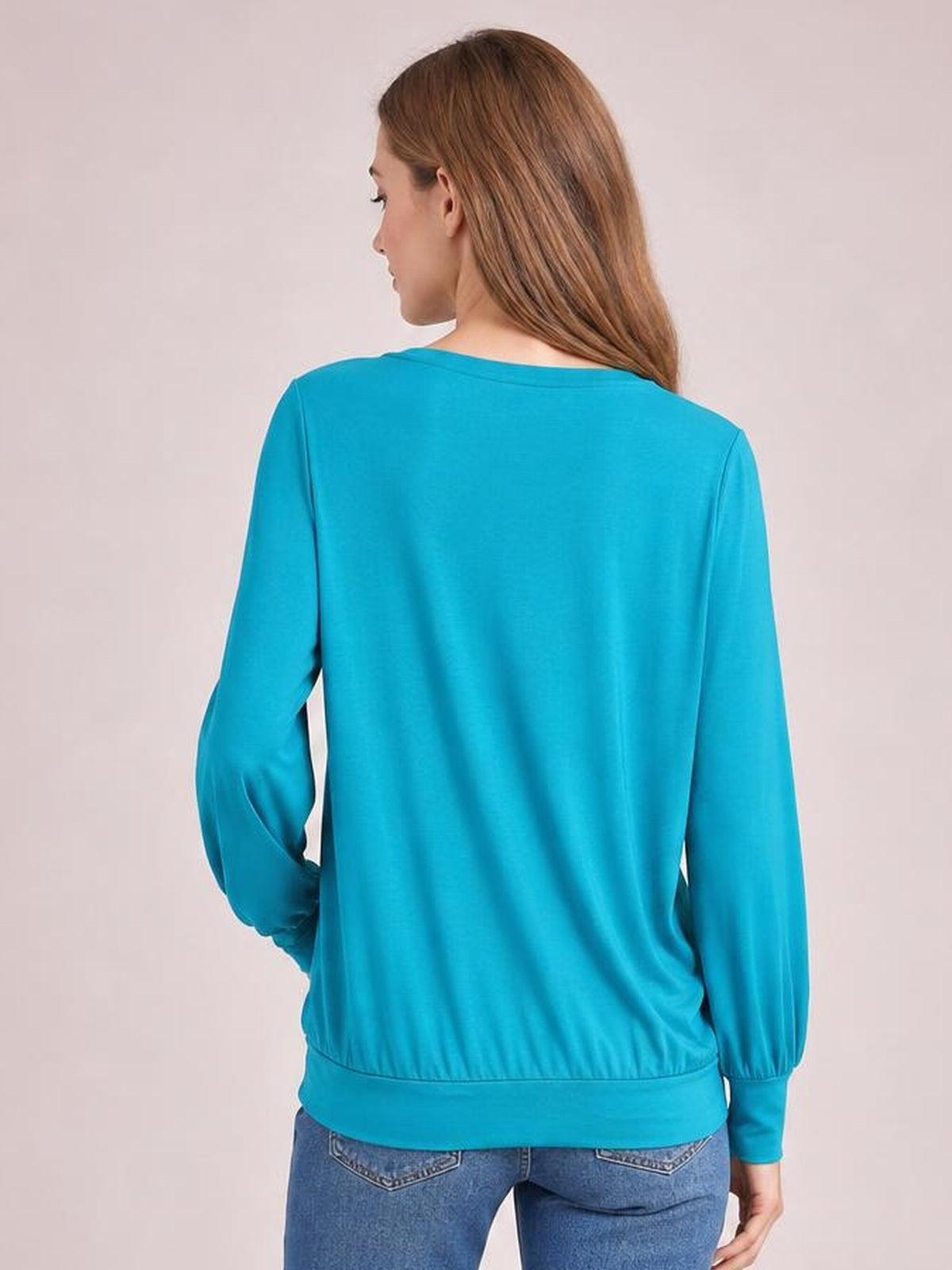Model shown from behind wearing a turquoise top with voluminous lantern sleeves, fitted cuffs, a wide hem band, and a relaxed silhouette.
