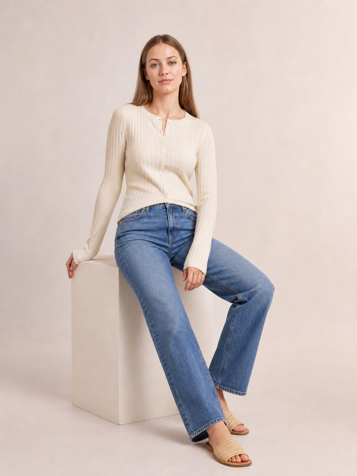 Model seated and wearing an ivory textured button-up round-neck top with long sleeves, a fitted stretchy silhouette, and visible front buttons.
