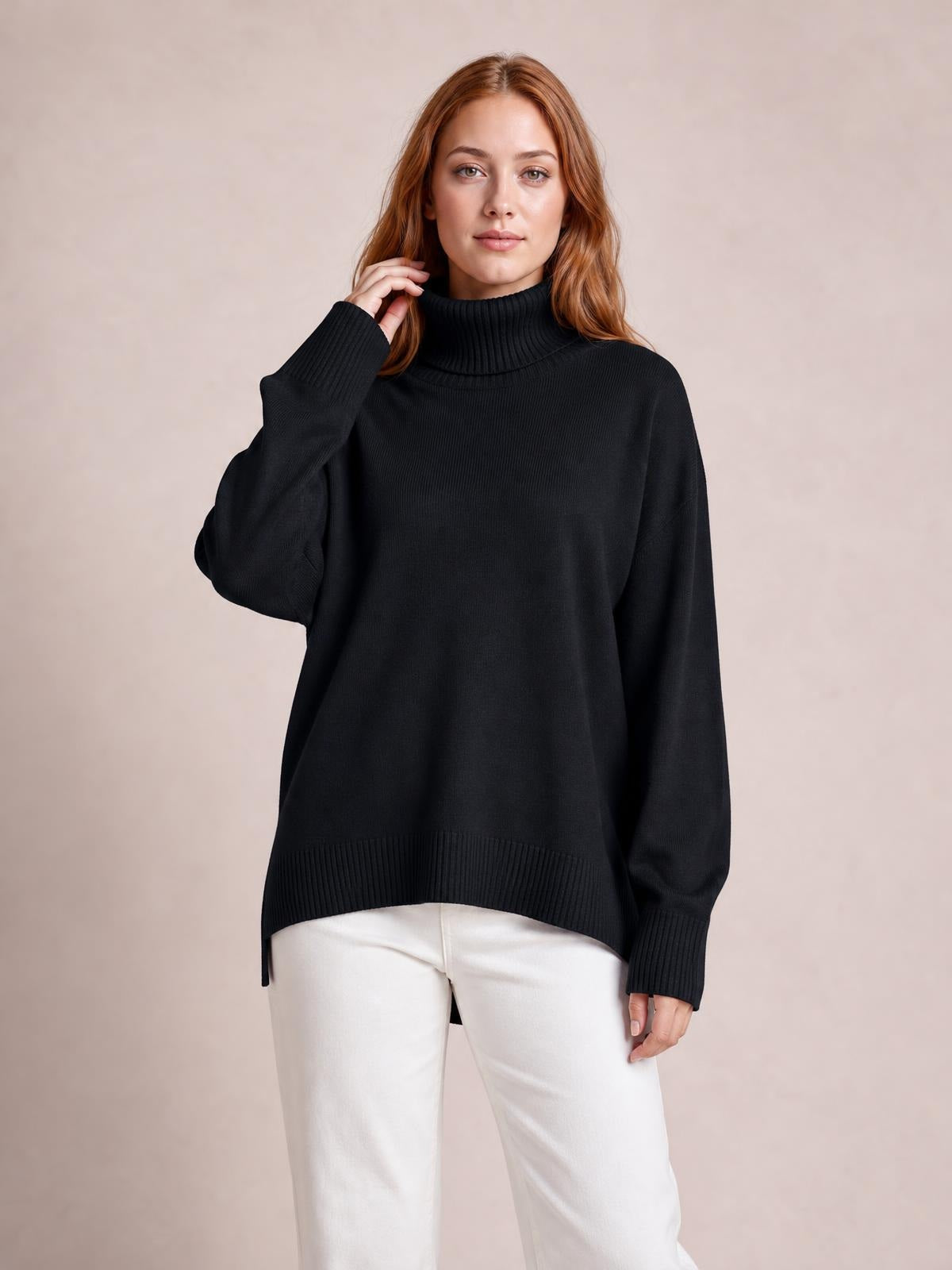Model touches the collar of a black turtleneck sweater with dropped shoulders, long sleeves, ribbed cuffs and hem, and a relaxed oversized silhouette.