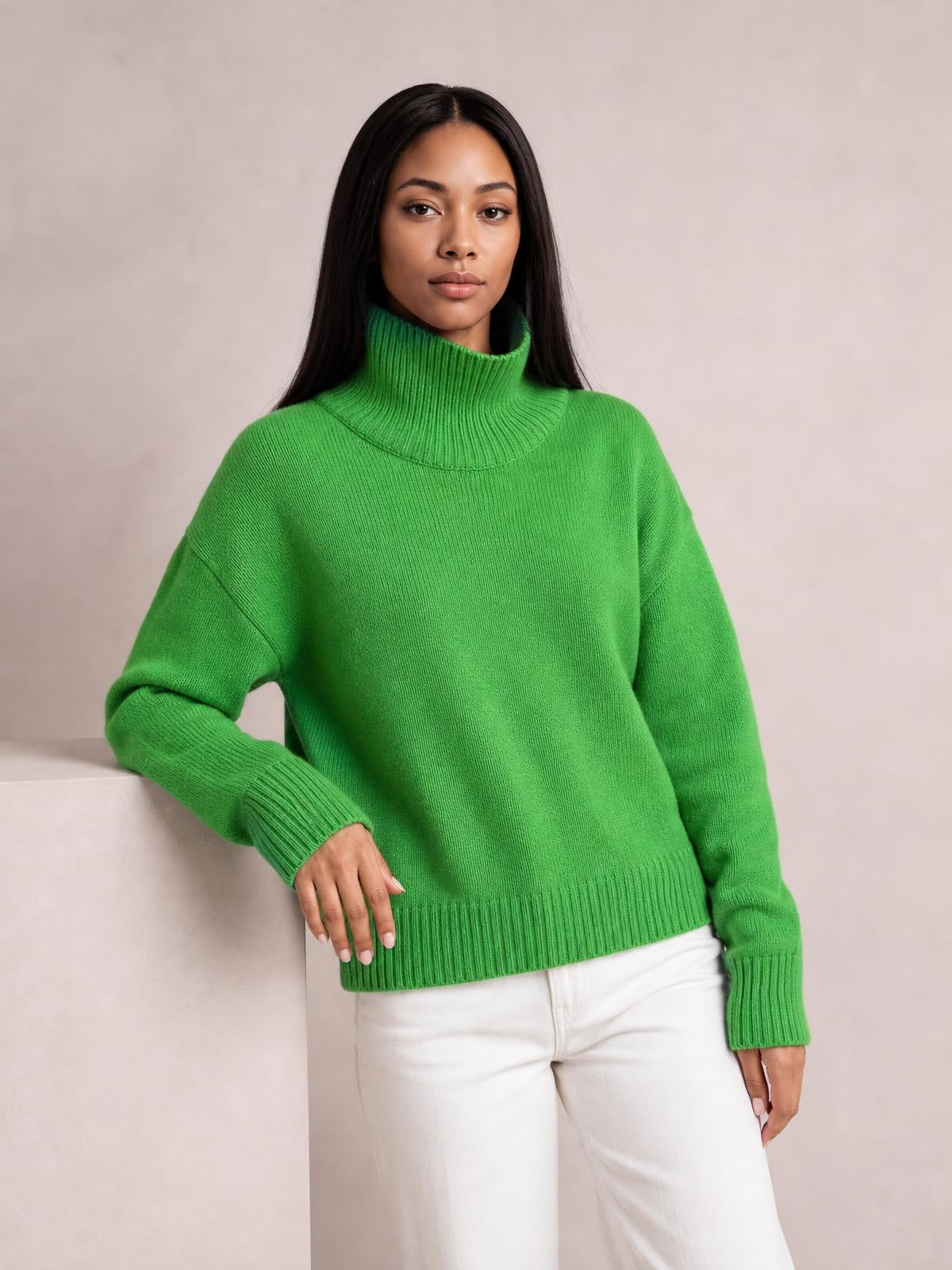 Model wearing a bright green turtleneck sweater with dropped shoulders, long sleeves, ribbed cuffs and hem, and a relaxed silhouette.