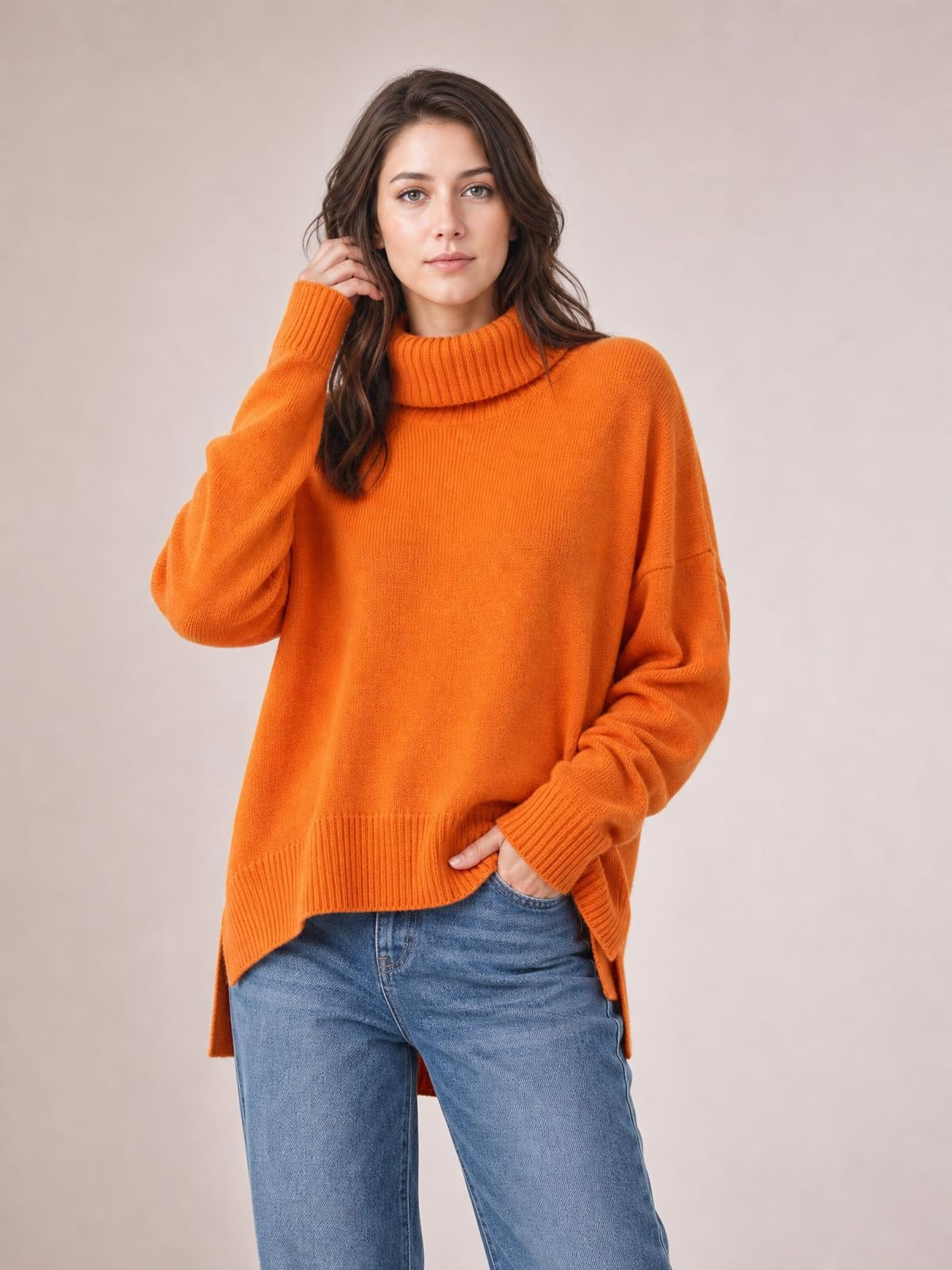 Model wearing an orange turtleneck sweater with dropped shoulders, long sleeves, ribbed cuffs and hem, and a relaxed oversized silhouette.