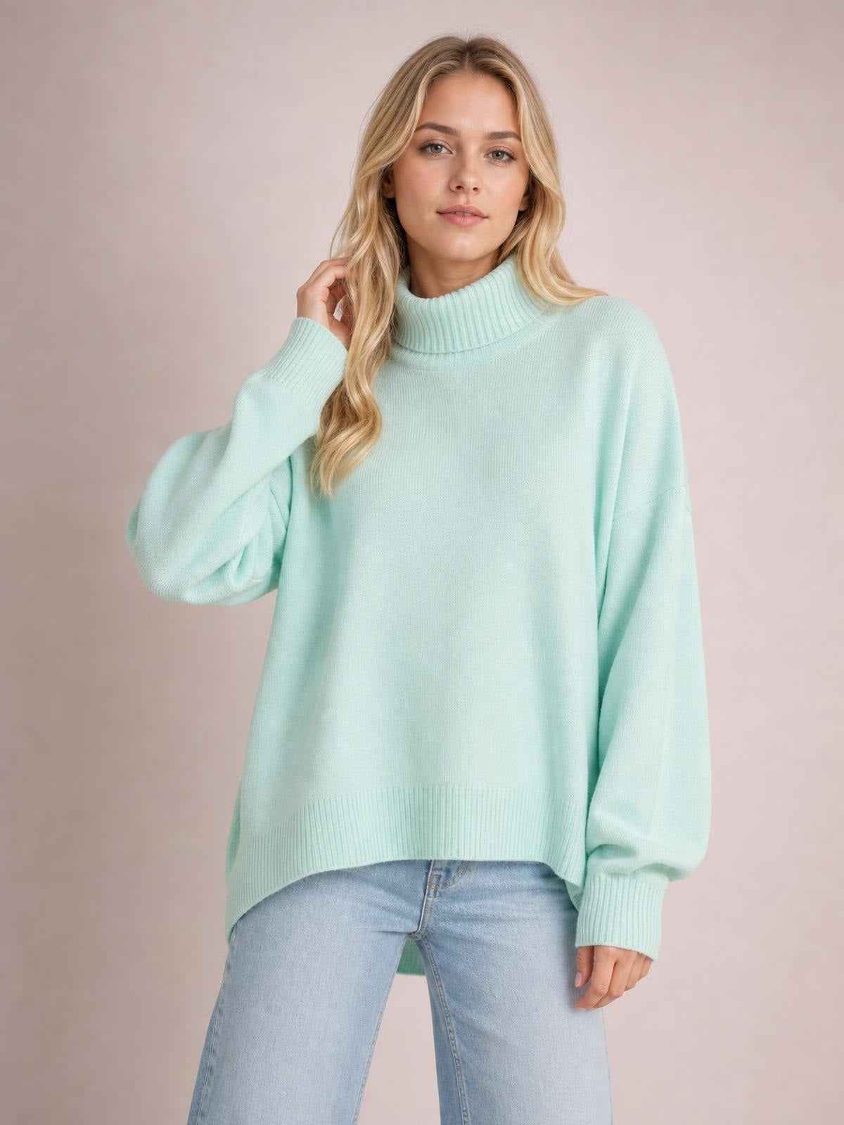 Model wearing a mint green turtleneck sweater with dropped shoulders, long sleeves, ribbed cuffs and hem, and a relaxed oversized silhouette.