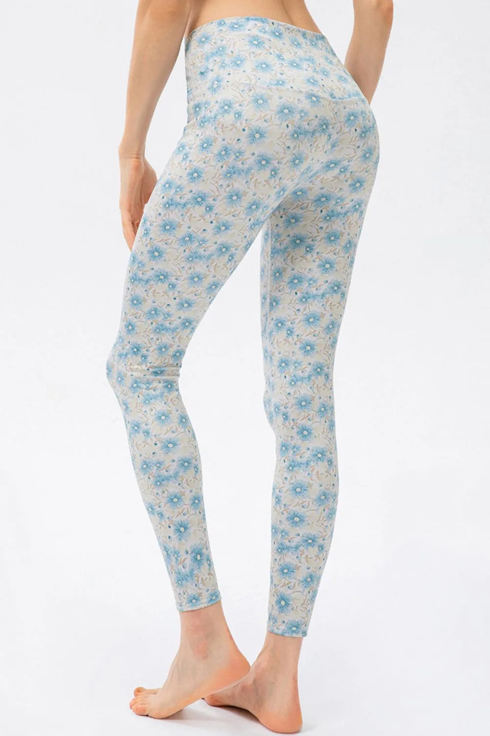 Model wears high-waist skinny active pants with a fitted ankle-length silhouette, moderate stretch, and a delicate blue floral print on a white base.