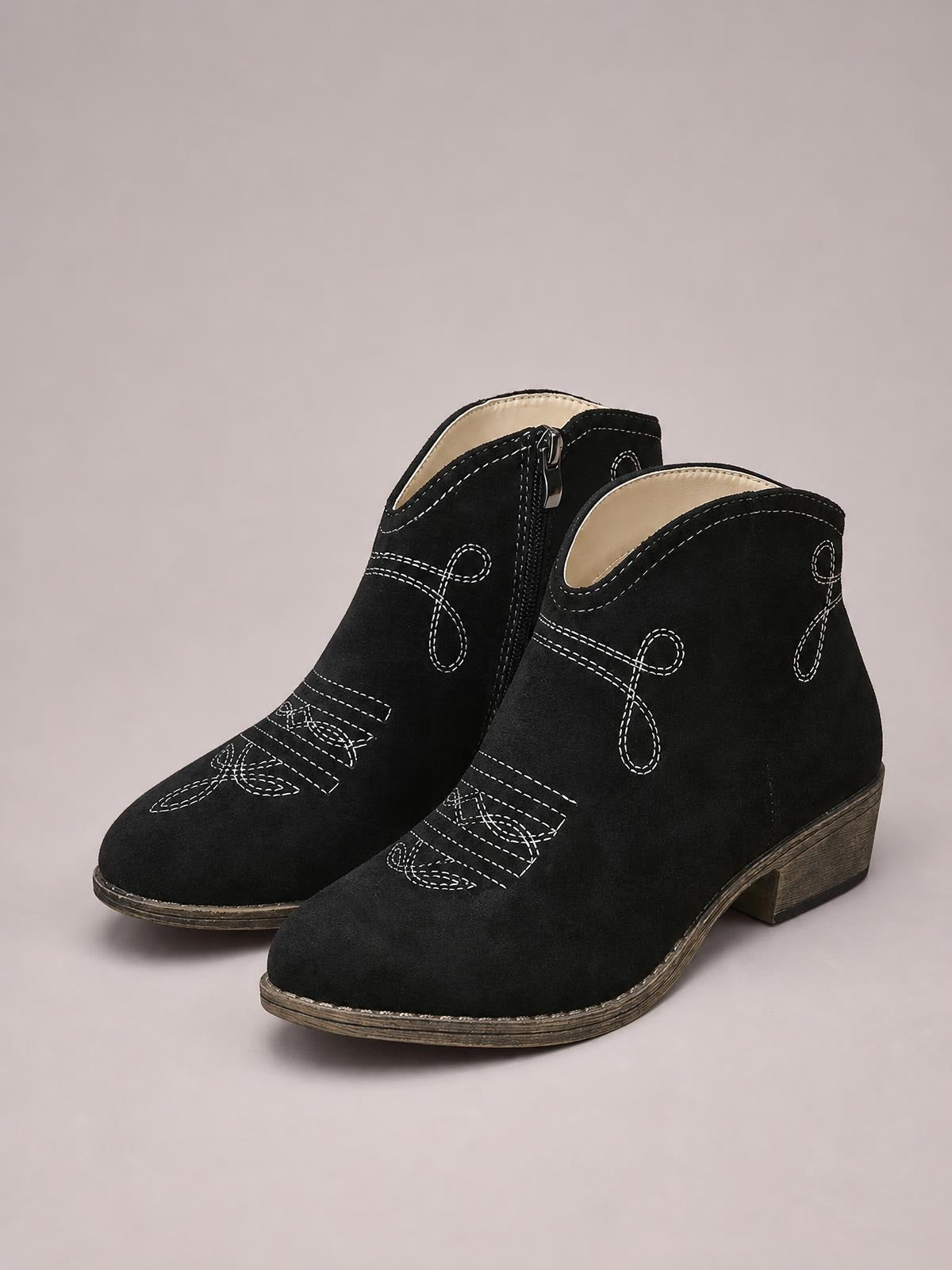 Black block heel ankle boots with rounded toes, contrasting white stitched detailing, side zippers, and mid-height stacked heels.