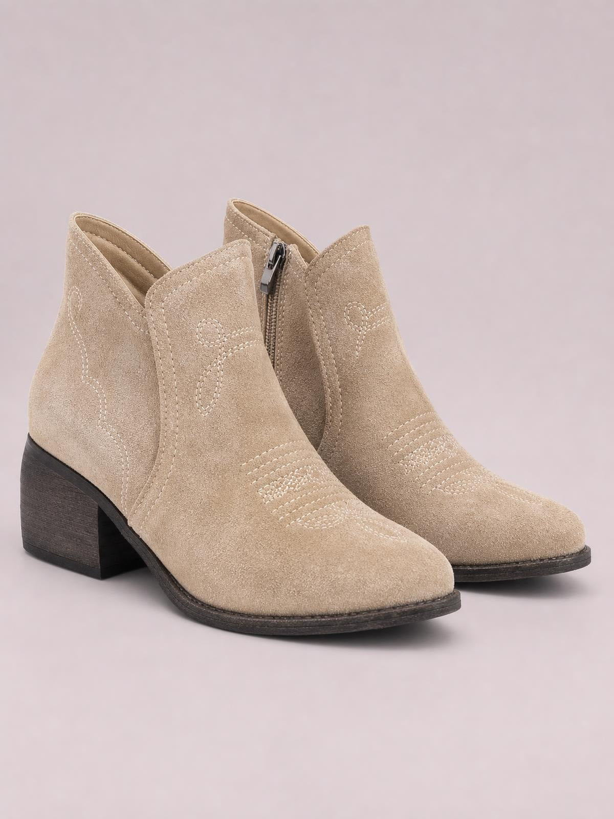 Beige PU leather ankle boots feature mid-height block heels, pointed toes, decorative stitched panels, and inner side zippers.