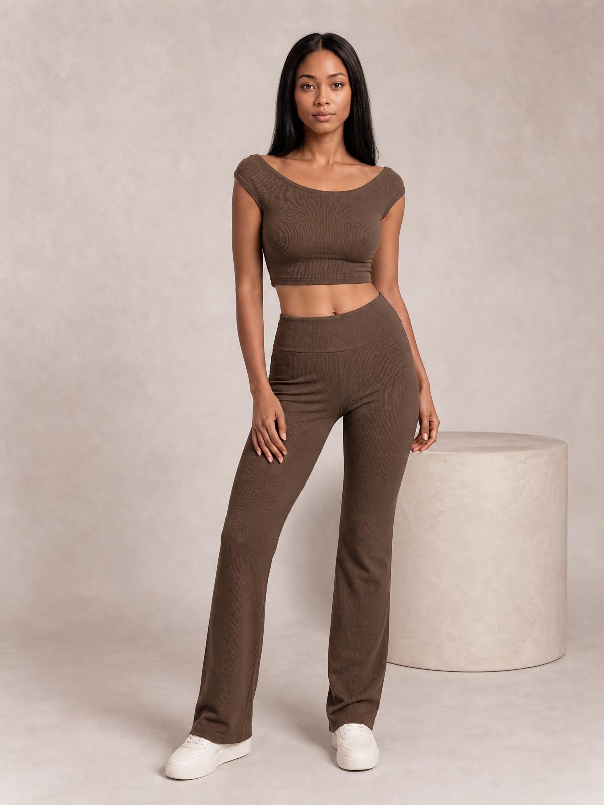 Model stands in a chocolate boat neck cap sleeve top and matching high-waisted straight-leg pants, creating a streamlined two-piece set with a cropped silhouette.