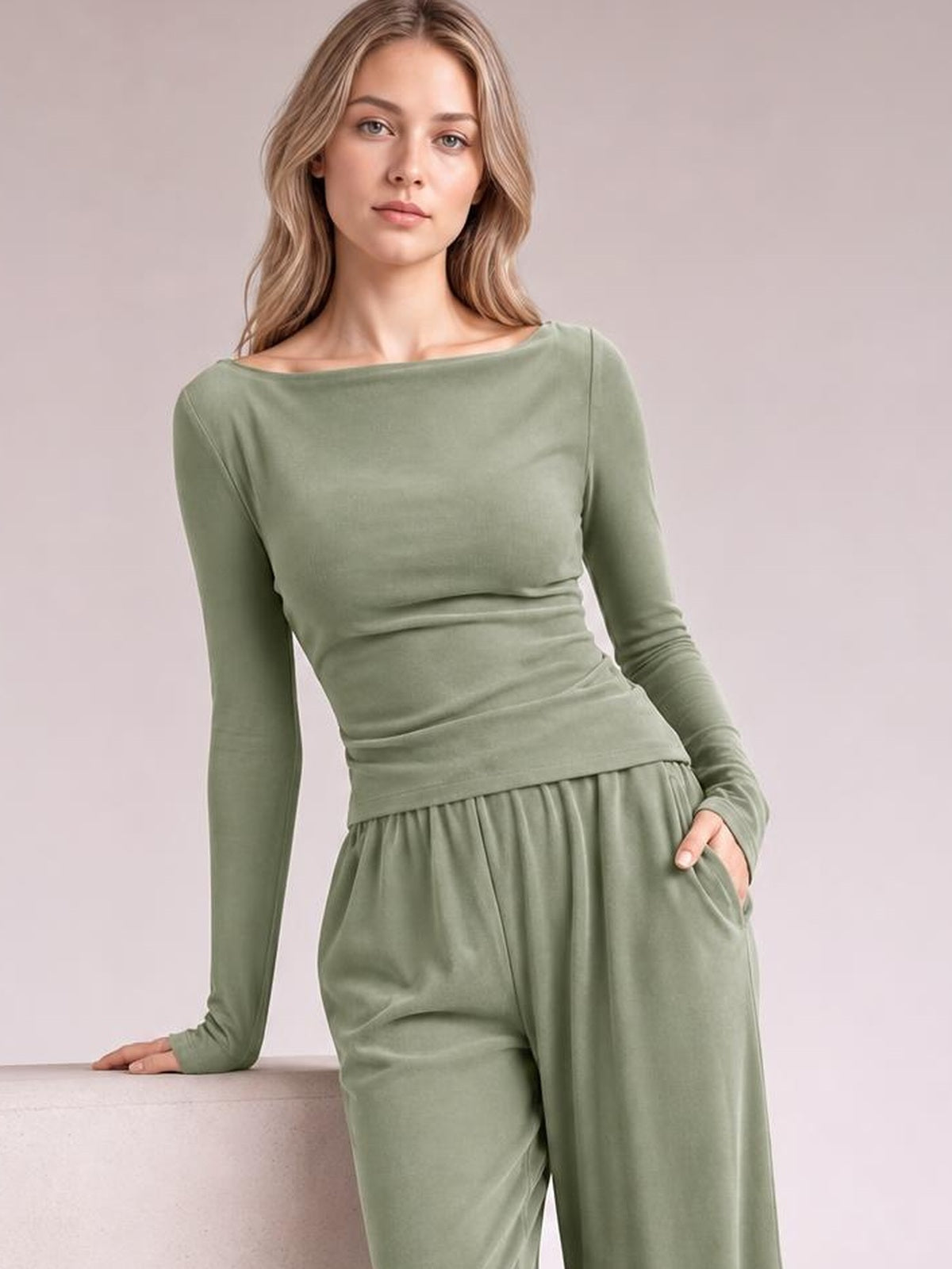 Model poses in a sage green boat-neck long-sleeve top and coordinating wide-leg pants, showing the relaxed silhouette and pocket detail.