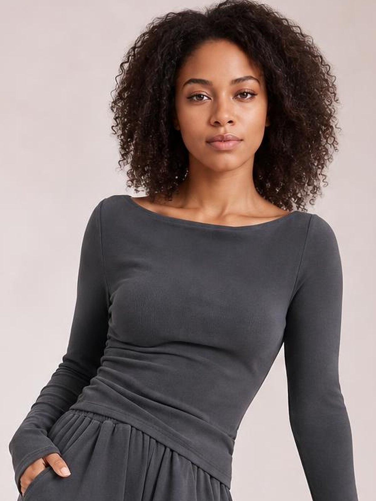 Model poses in a dark gray boat-neck long-sleeve top and coordinating pants set, showing a fitted top with a relaxed gathered waistband.