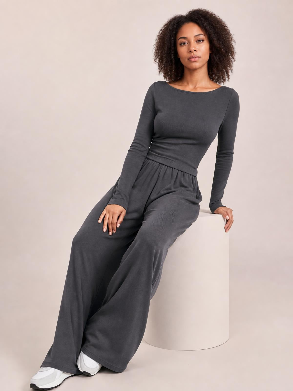 A model sits in a dark gray boat-neck long-sleeve top and coordinating wide-leg pants set, showing its fitted top and relaxed silhouette.