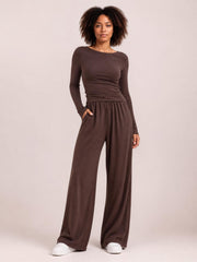 Model poses in a brown boat-neck long-sleeve top and coordinating wide-leg pants set, featuring a fitted silhouette, elastic waist, and side pockets.
