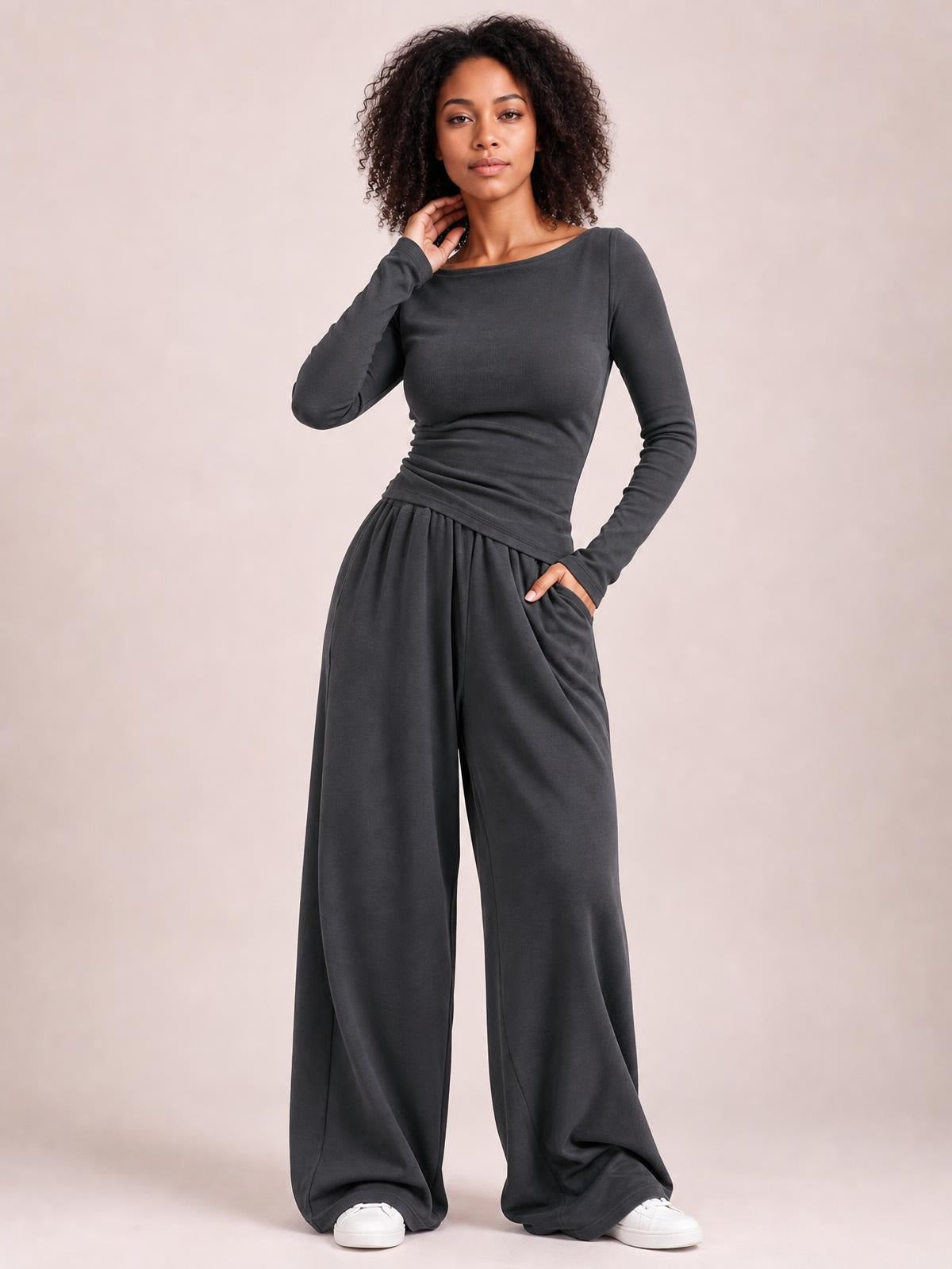 Model poses in a charcoal boat-neck long-sleeve top and coordinating wide-leg pants set, with a fitted top and relaxed flowing silhouette.